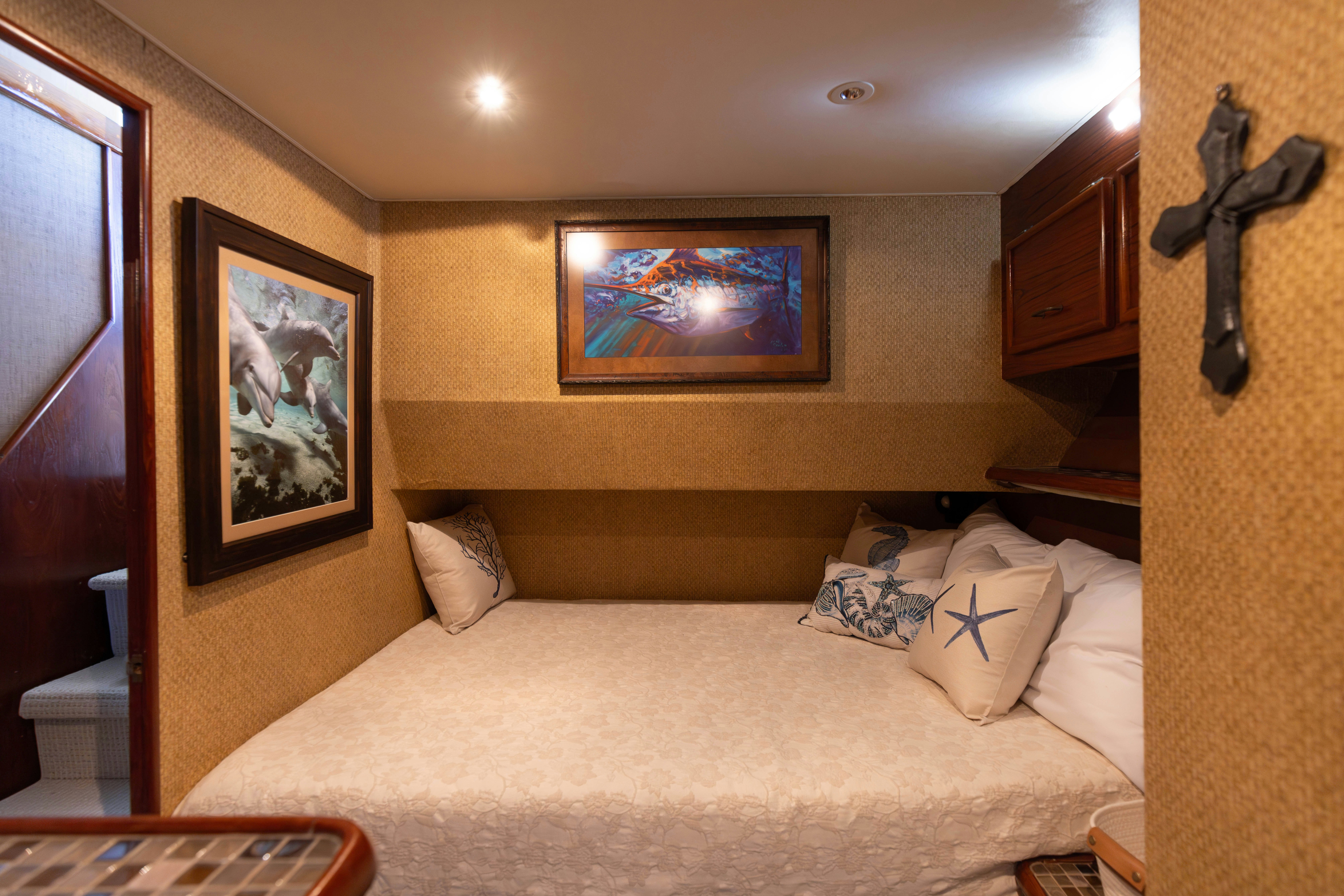 a bed with a white sheet and pillows in a room with art on the wall aboard LUCKY MARLIN Yacht for Sale