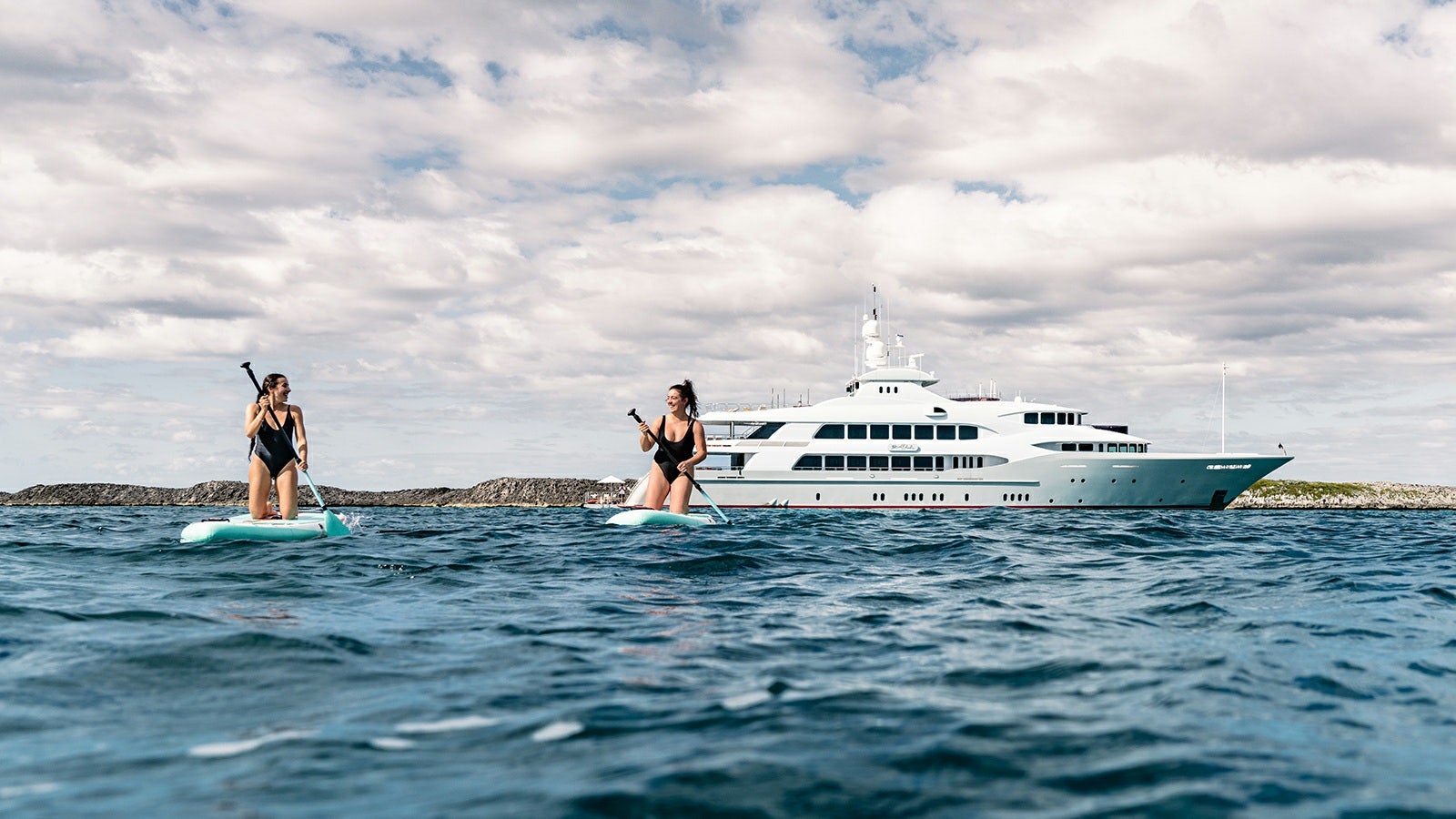 a woman and a man on a surfboard in the ocean aboard IRON BLONDE Yacht for Charter