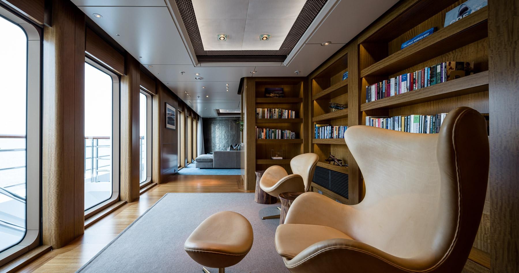 a room with a bookcase and chairs aboard OCTOPUS Yacht for Charter