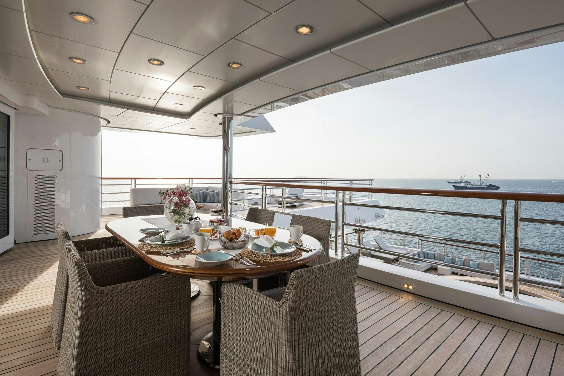 a table on a deck overlooking a large body of water aboard OCTOPUS Yacht for Charter