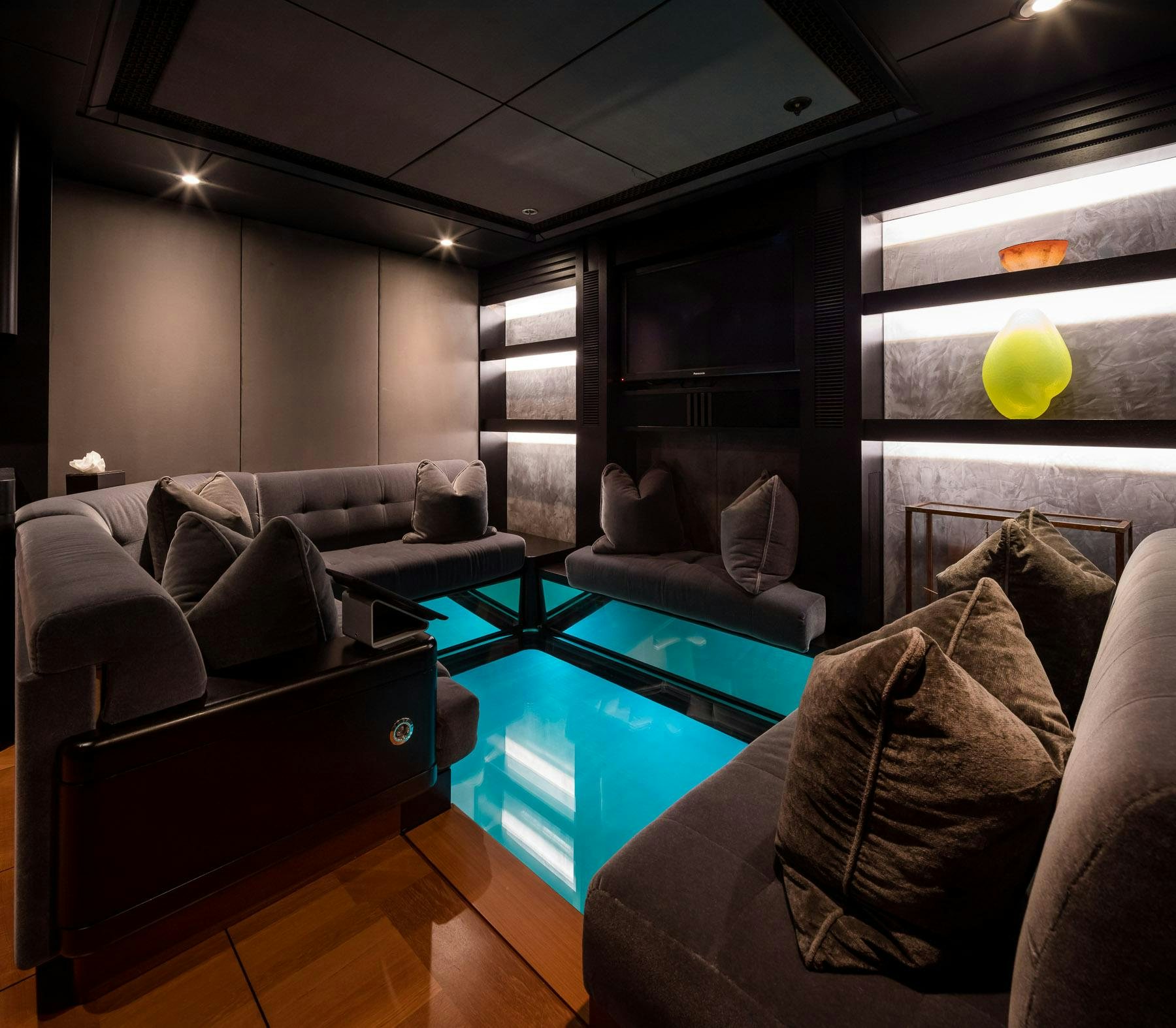 a living room with a large blue table and a black couch aboard OCTOPUS Yacht for Charter