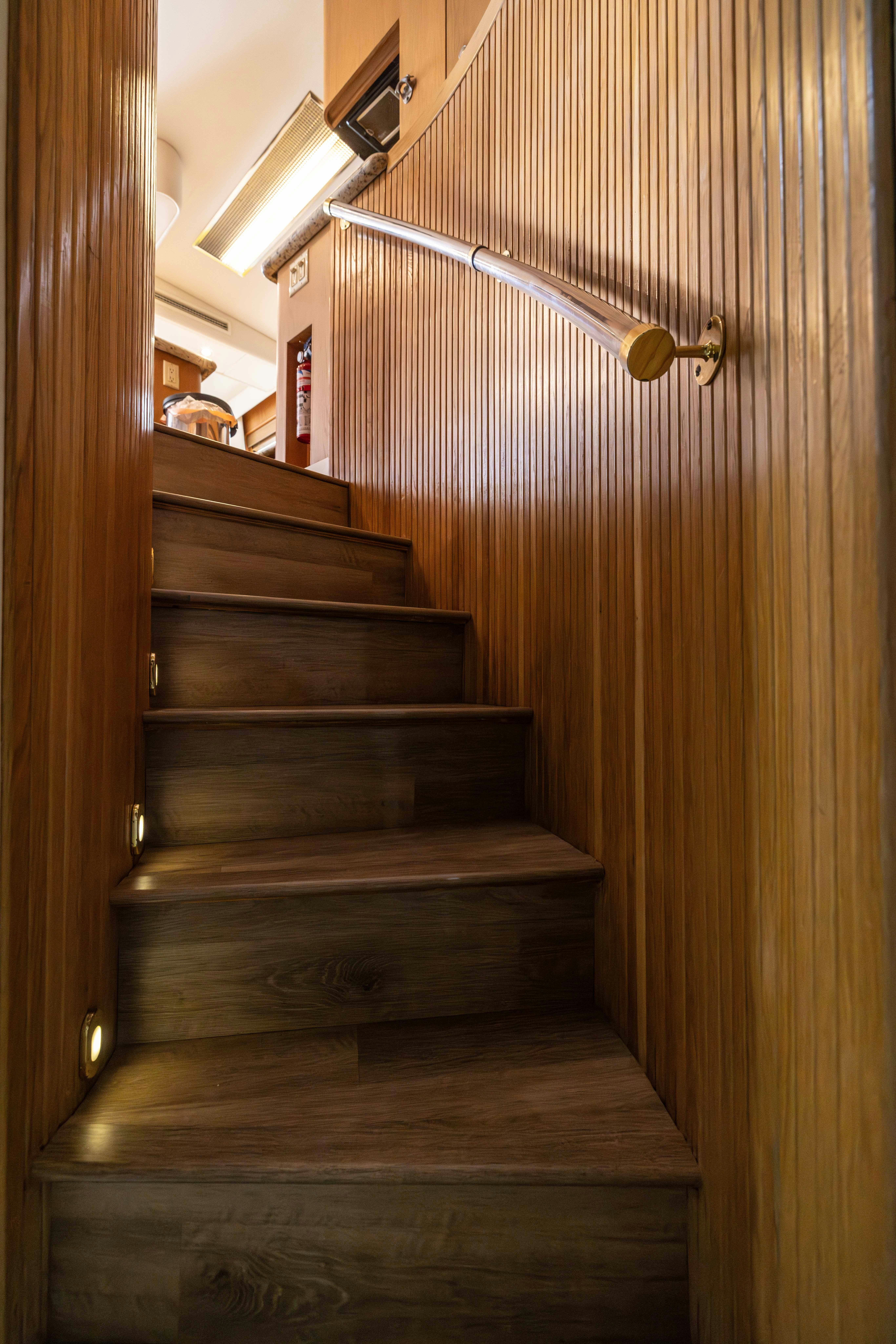 a wooden staircase with a metal railing aboard PREMIUM Yacht for Sale