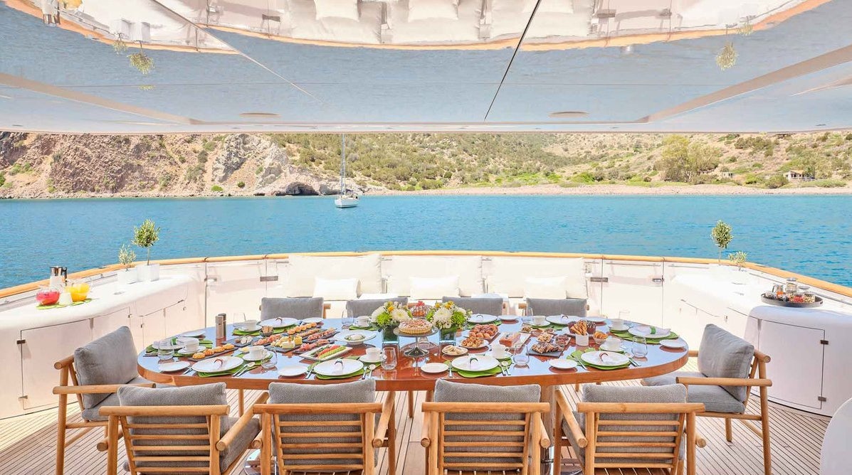 a table set for a meal on a patio overlooking a body of water aboard MAMMA MIA Yacht for Charter