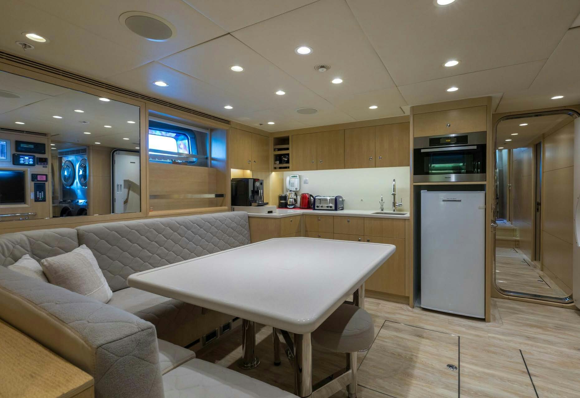 a large kitchen with a large white sofa and a large white table aboard SALVAJE Yacht for Sale