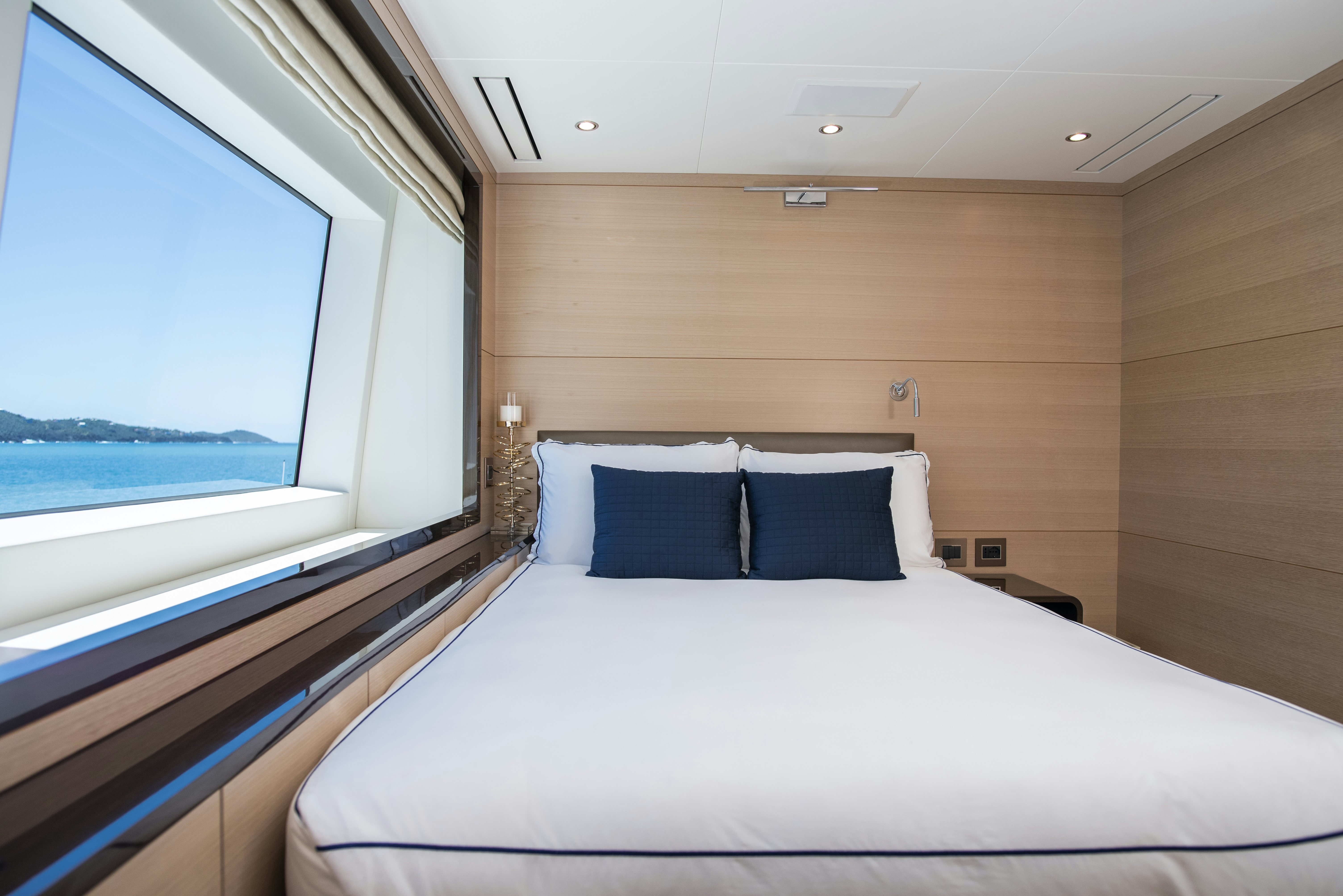 a bed with a white sheet and a window with a view of the ocean aboard WABASH Yacht for Sale