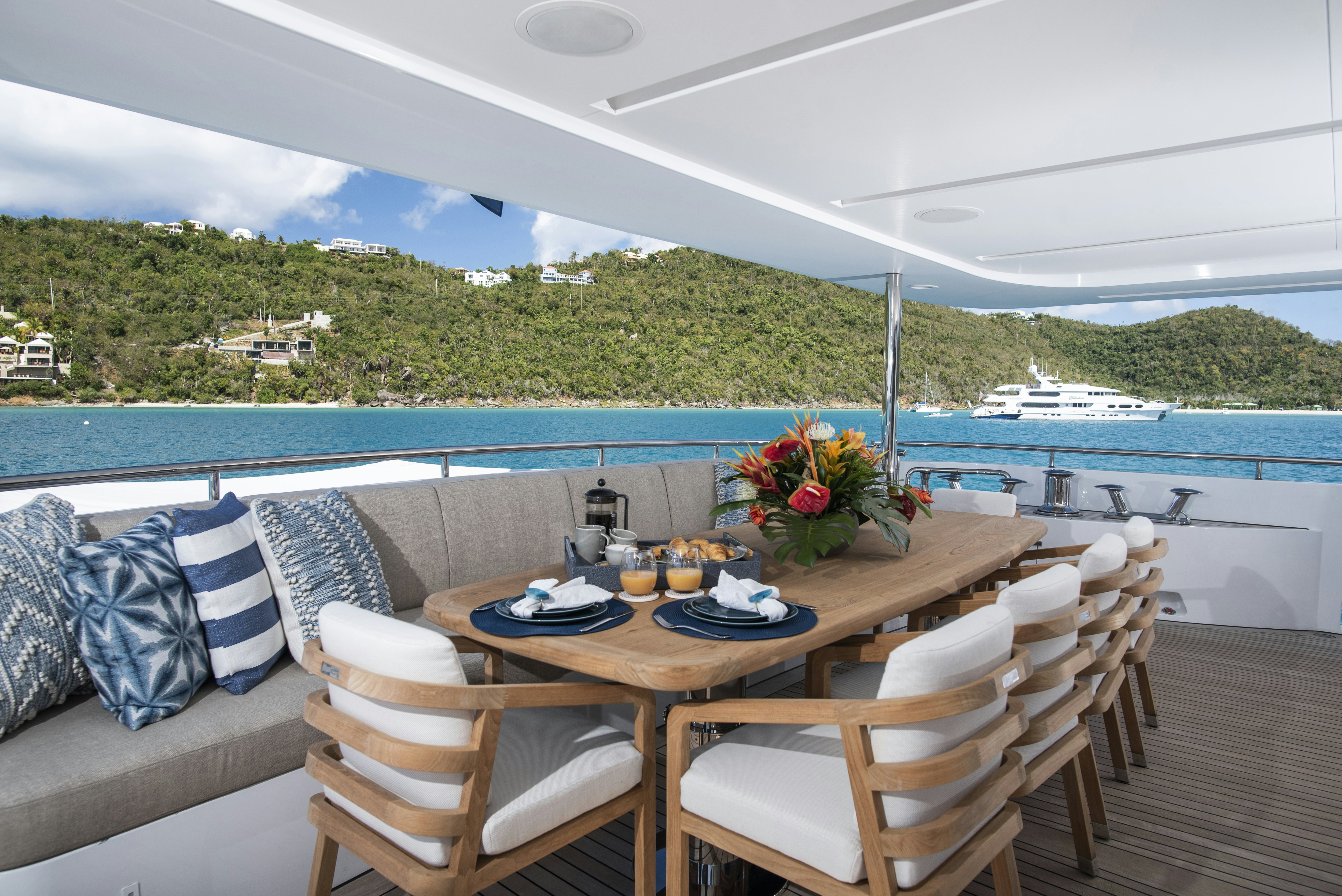 a table set for a meal on a deck overlooking a body of water aboard WABASH Yacht for Sale