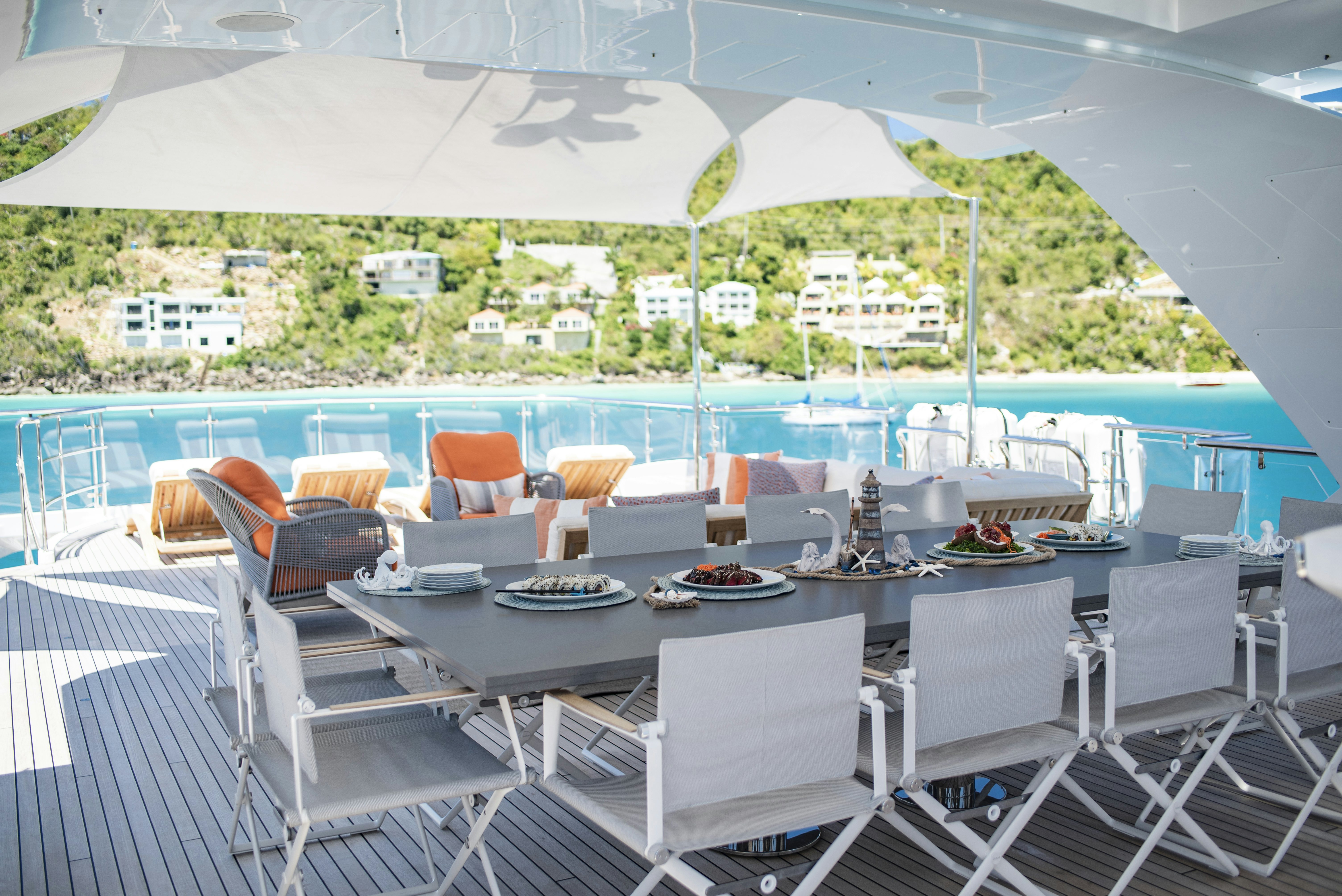 a table set for a meal on a deck overlooking a pool aboard WABASH Yacht for Sale