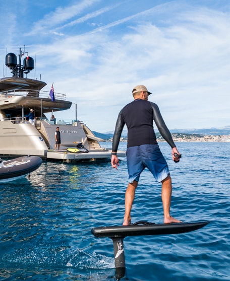 a person standing on a surfboard aboard THE PALM Yacht for Charter