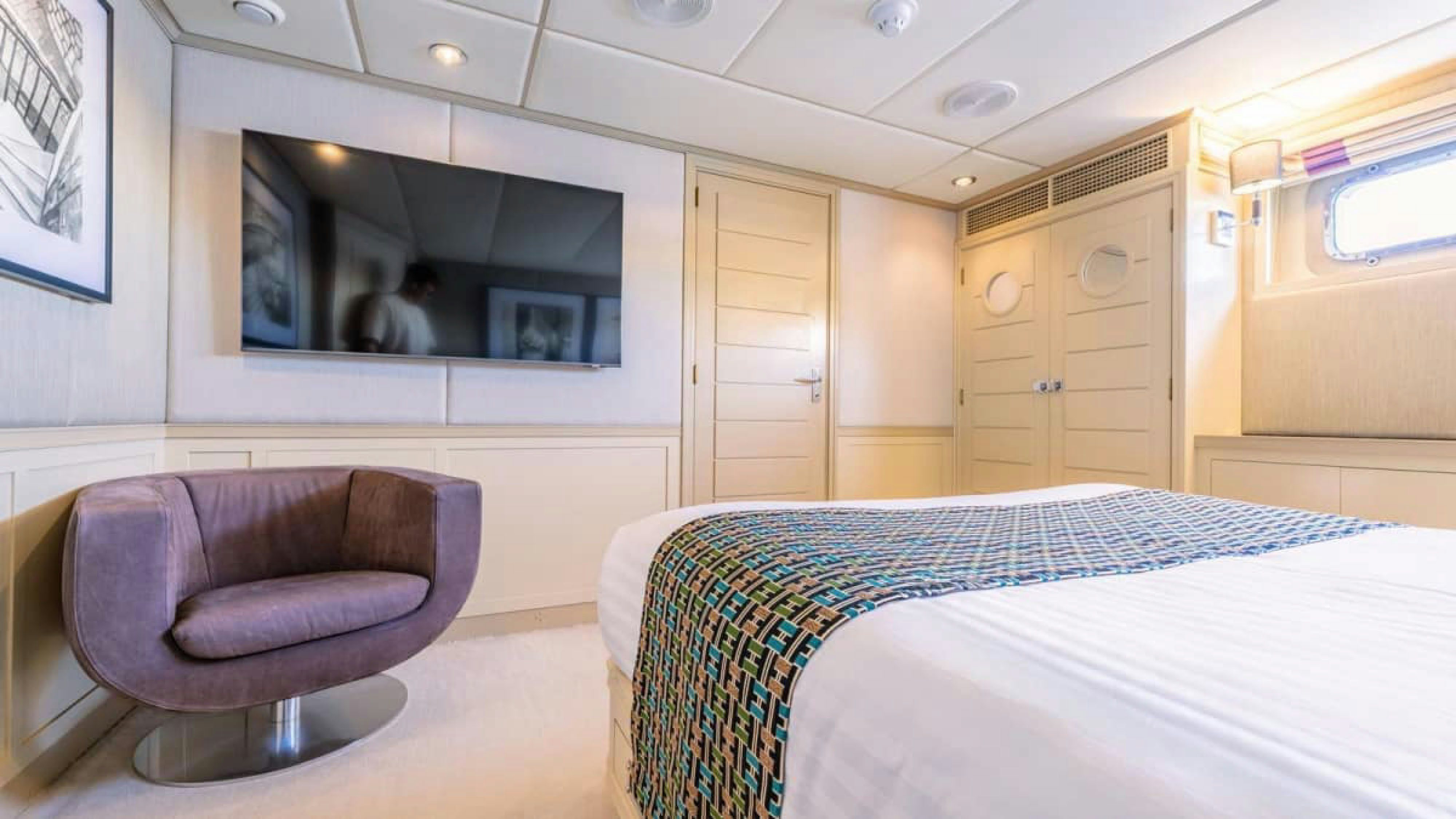 a bedroom with a bed and a chair aboard VICTORY Yacht for Charter