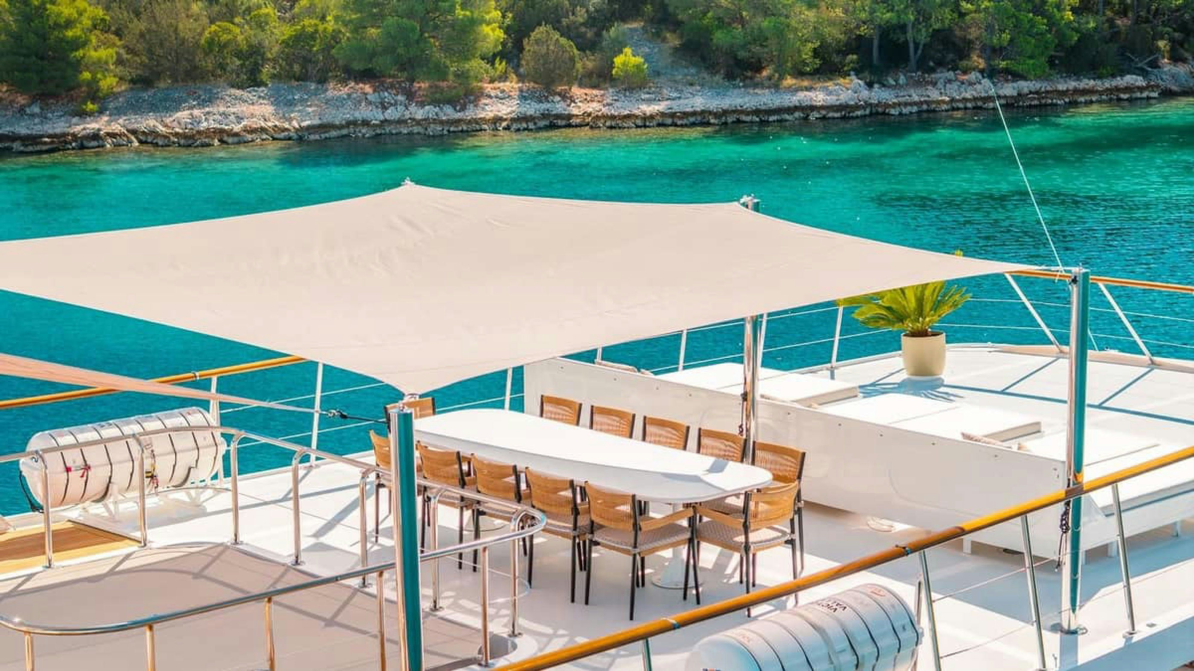 a deck with chairs and tables on it by a body of water aboard VICTORY Yacht for Charter