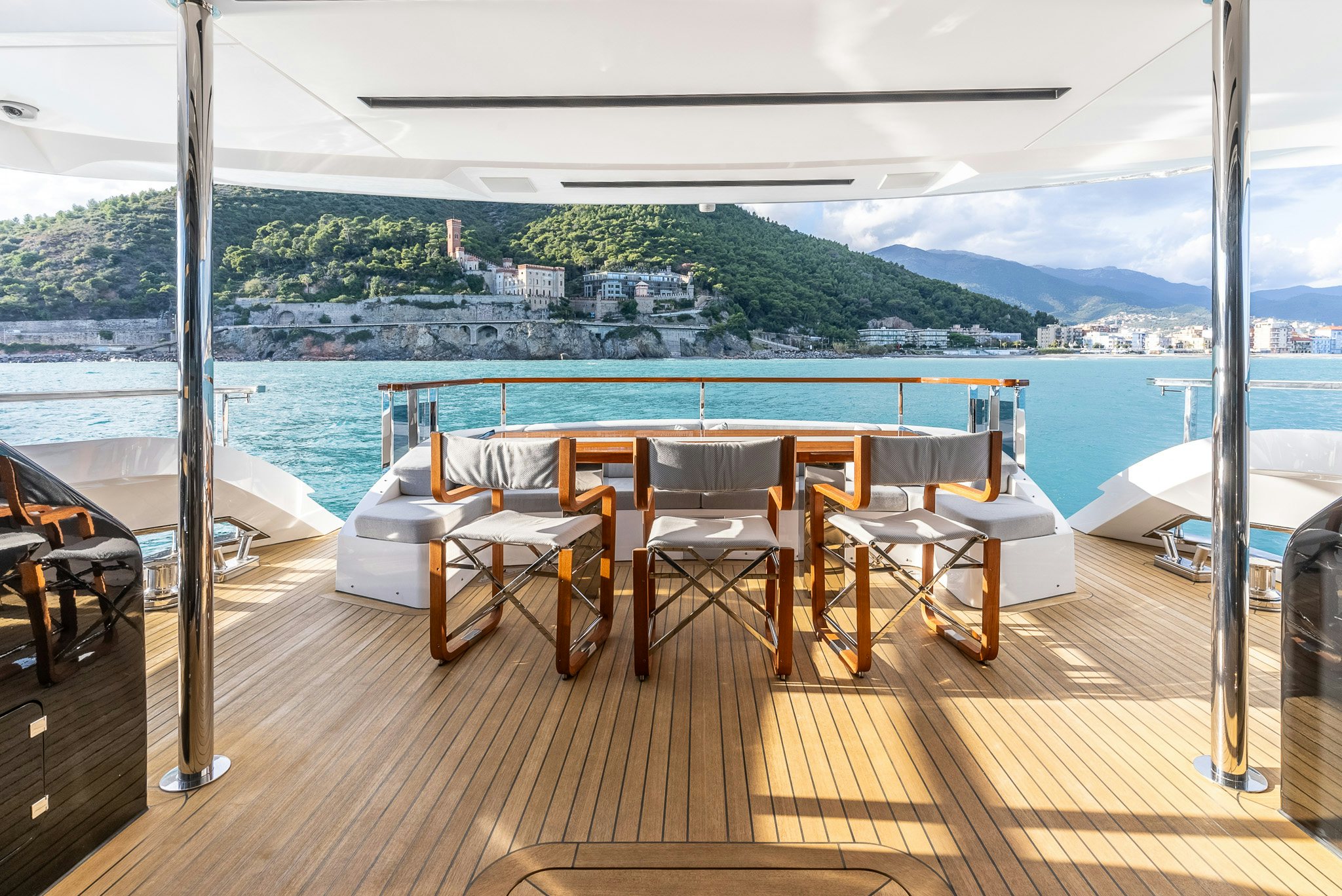 a room with a table and chairs on a deck overlooking a body of water aboard CADET V Yacht for Sale