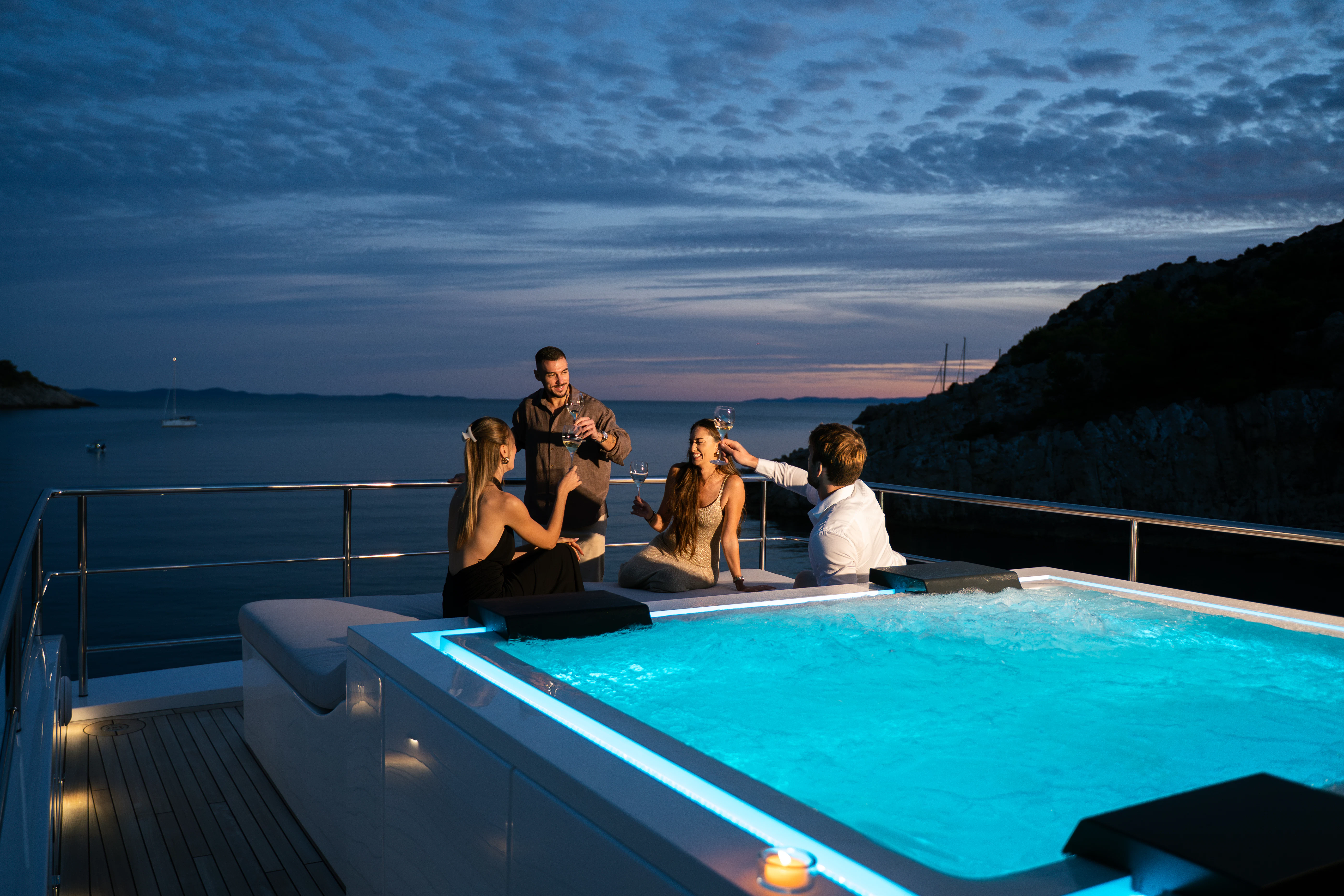 a group of people sitting on a pool table on a balcony overlooking a body of water aboard RENATA Yacht for Charter