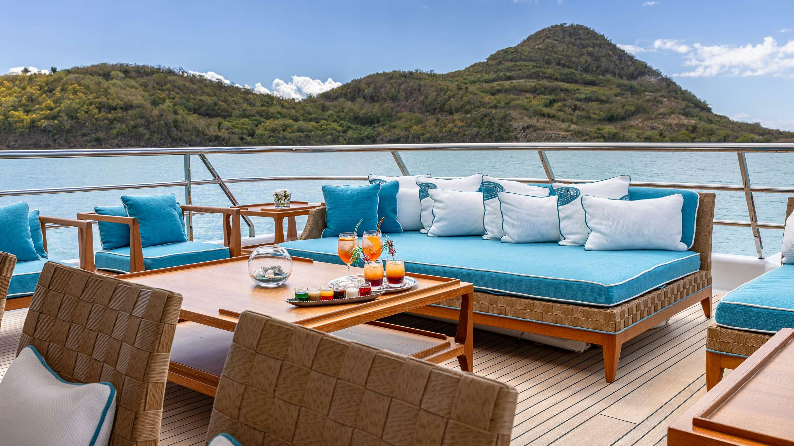 a large blue couch on a balcony overlooking a body of water aboard DEEP BLUE Yacht for Charter