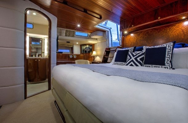 a bed with a white sheet and pillows in a room with a mirror aboard SORCERER II Yacht for Sale