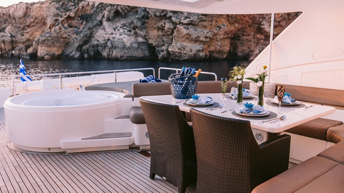 a table with chairs and a pool aboard MELI Yacht for Charter