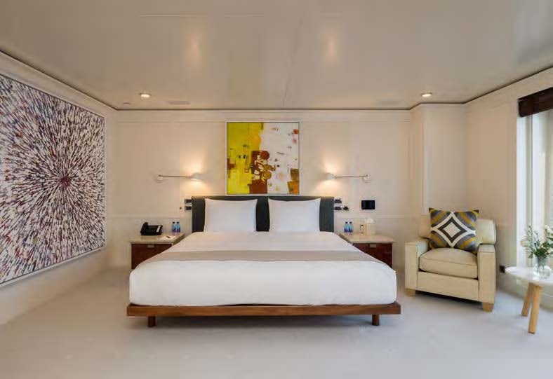 a bedroom with a bed and a chair aboard HBC Yacht for Sale
