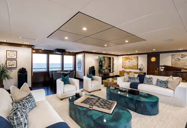 a living room with a large glass table and a large window aboard HBC Yacht for Sale