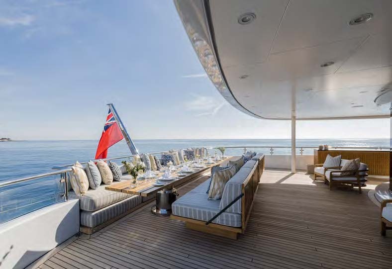 a deck with a large flag and a beach view aboard HBC Yacht for Sale