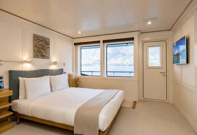 a bedroom with a bed and a window aboard HBC Yacht for Sale