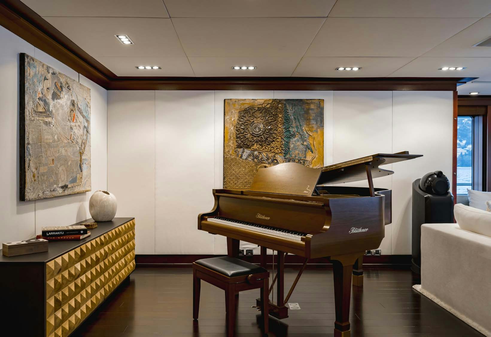 a room with a piano and paintings on the wall aboard HBC Yacht for Sale