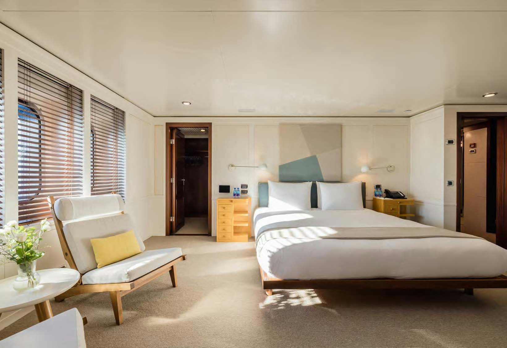 a bedroom with a bed and a chair aboard HBC Yacht for Sale
