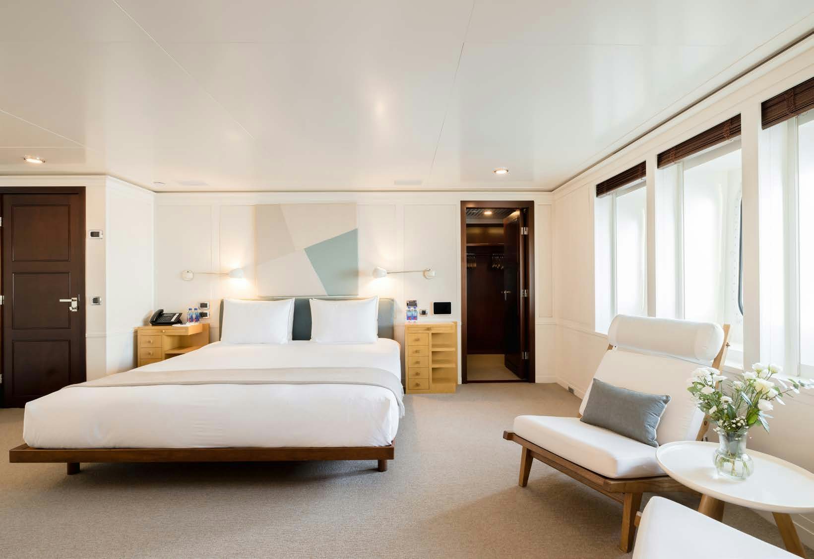 a bedroom with a bed and a chair aboard HBC Yacht for Sale