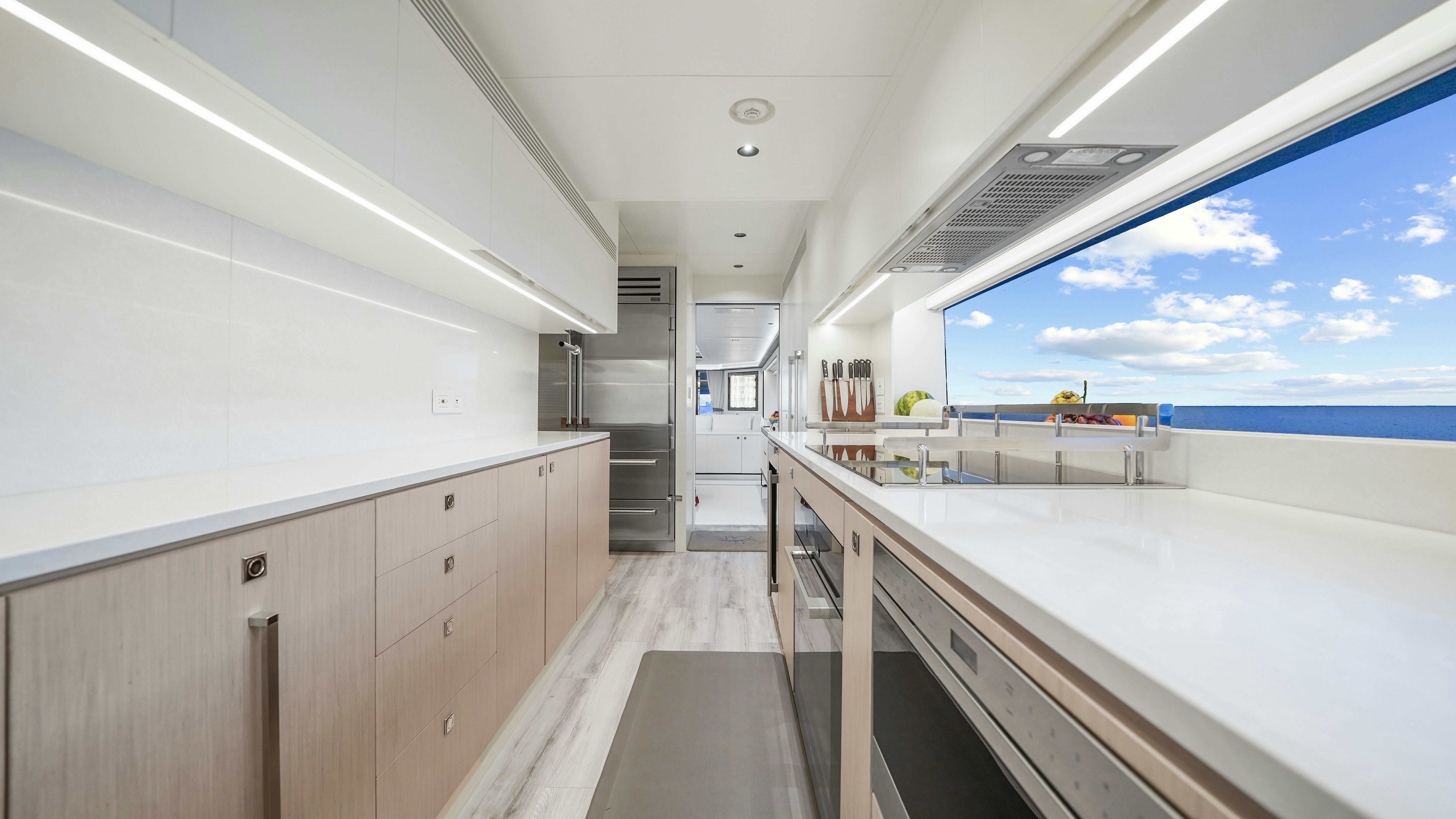 a long white kitchen with a large window aboard MISS MICHELLE Yacht for Sale