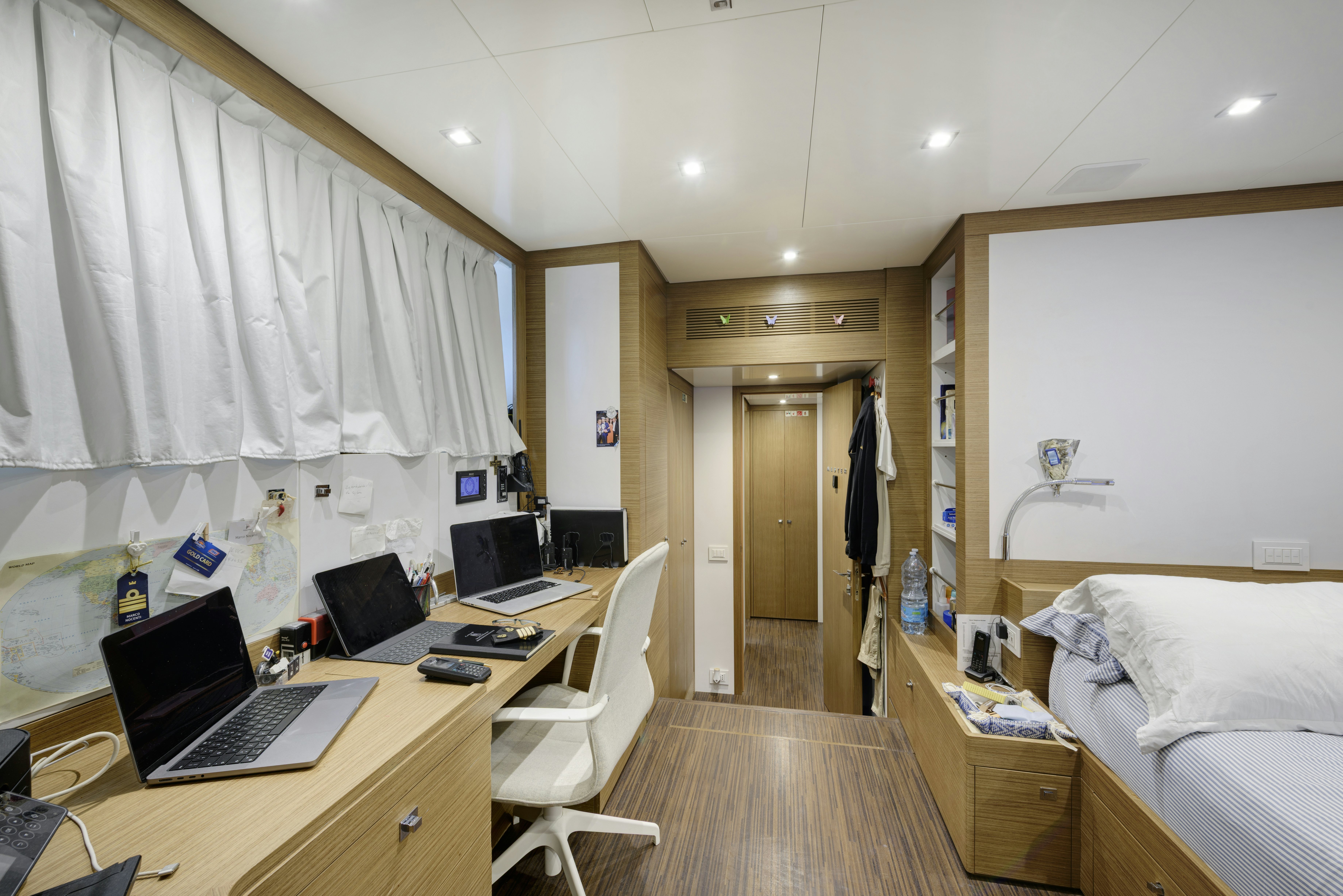 a bedroom with a bed desk and a laptop aboard SERENITY Yacht for Sale