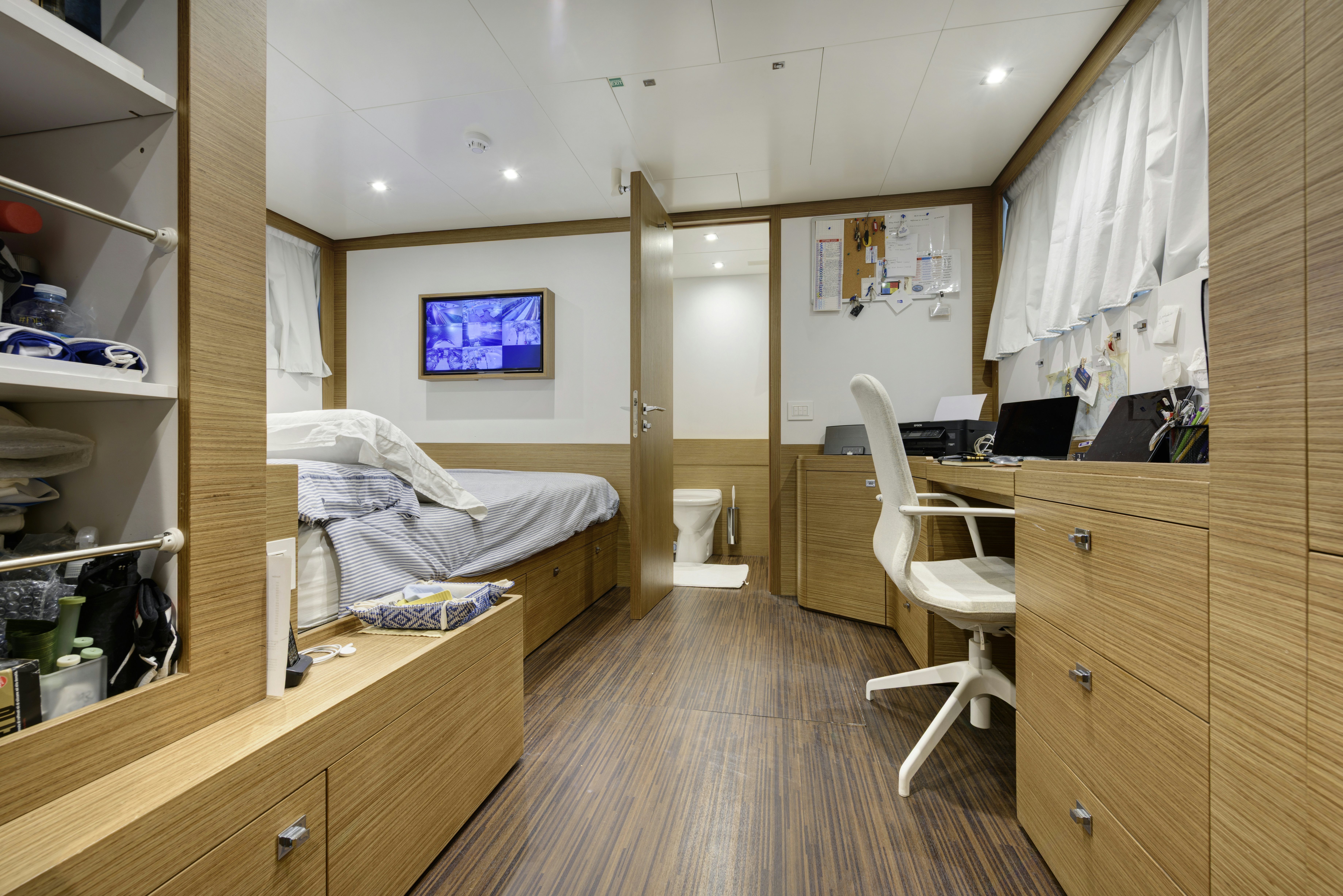 a bedroom with a desk and a bed aboard SERENITY Yacht for Sale
