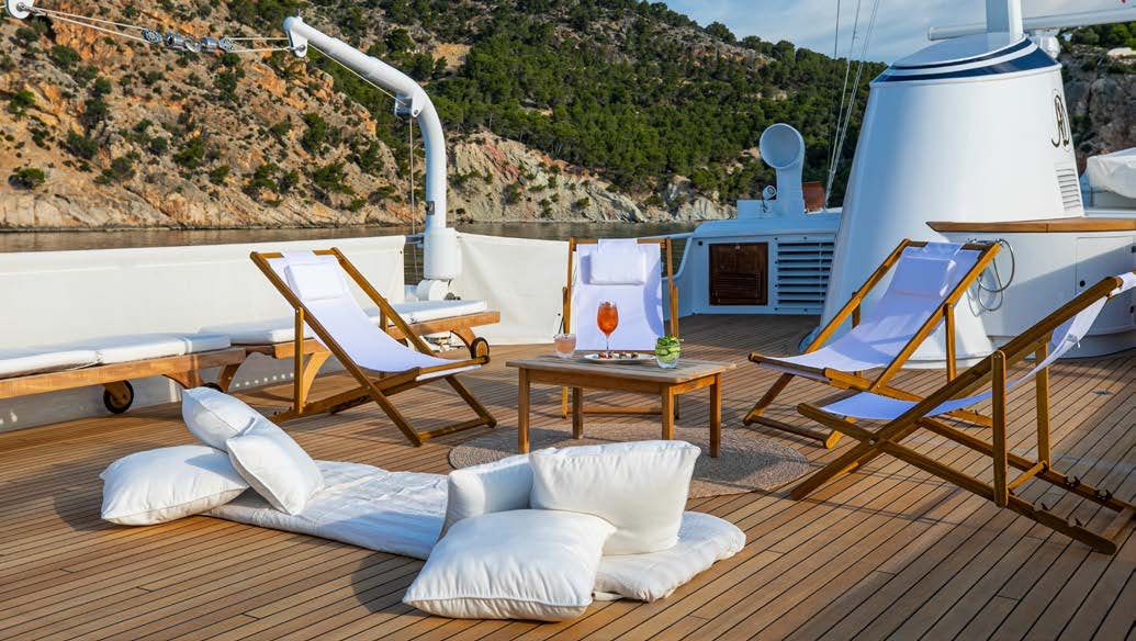 a room with a bed and a table and chairs aboard HEAVENLY DAZE Yacht for Charter