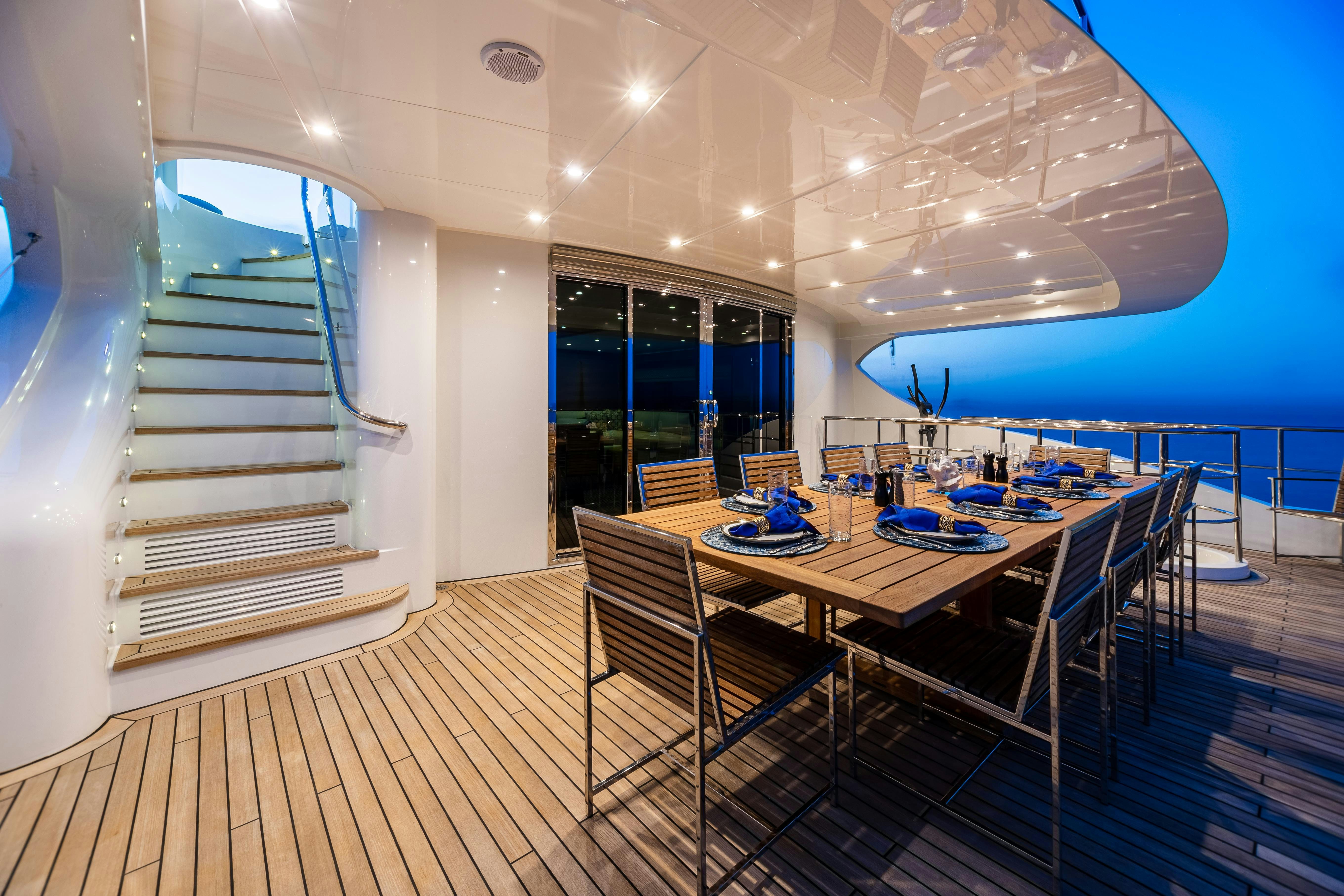 a long wooden deck with a table and chairs and a staircase aboard SWEET CAROLINE Yacht for Charter