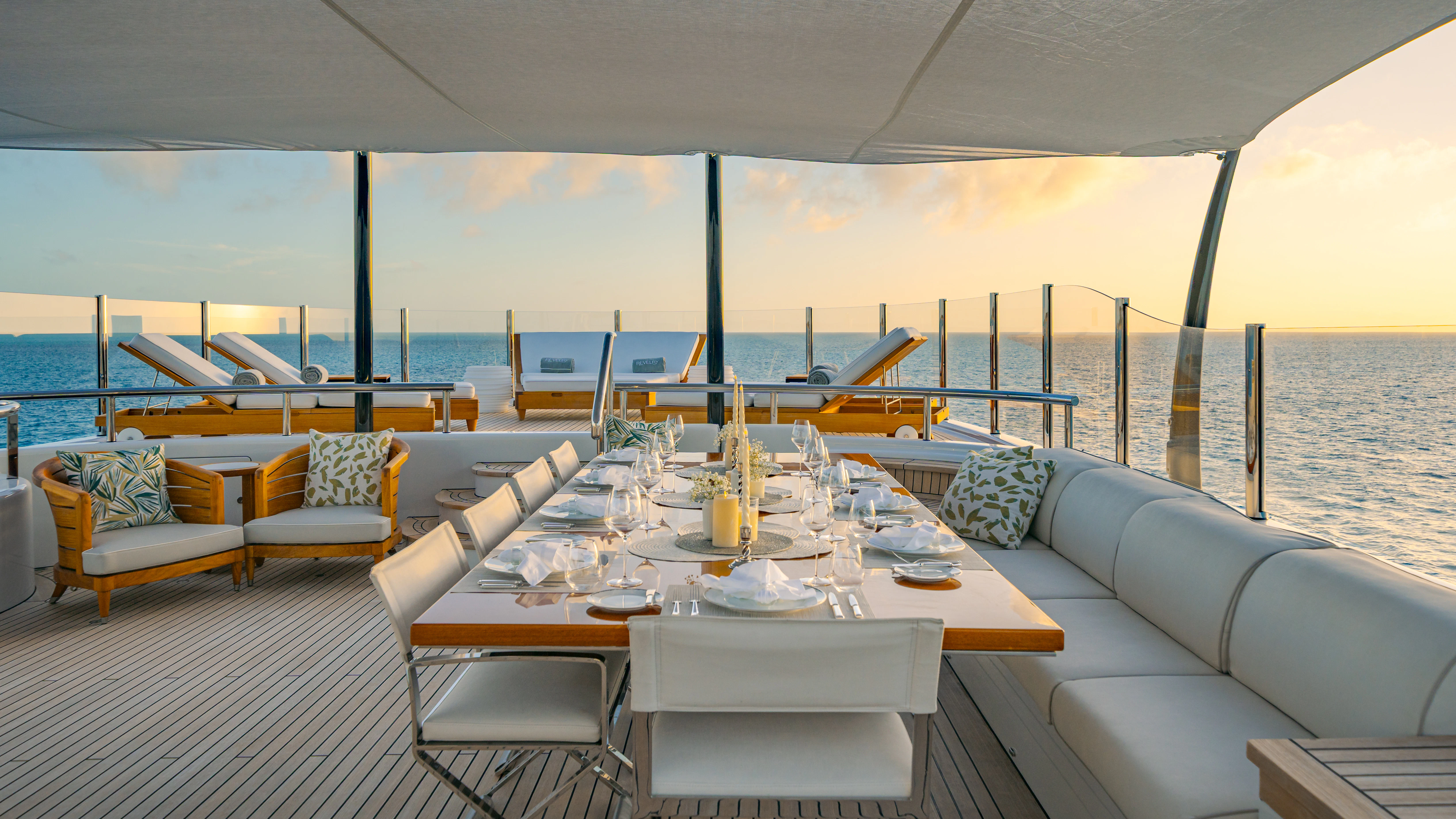 a large white table with chairs on it next to a large body of water aboard REVELRY Yacht for Charter
