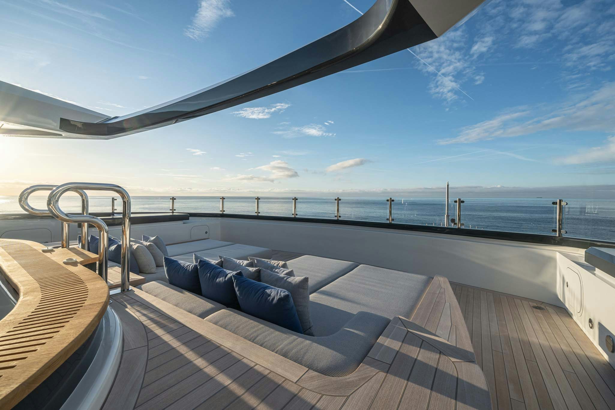 a deck with a large body of water and a large boat in the background aboard MALIA Yacht for Charter