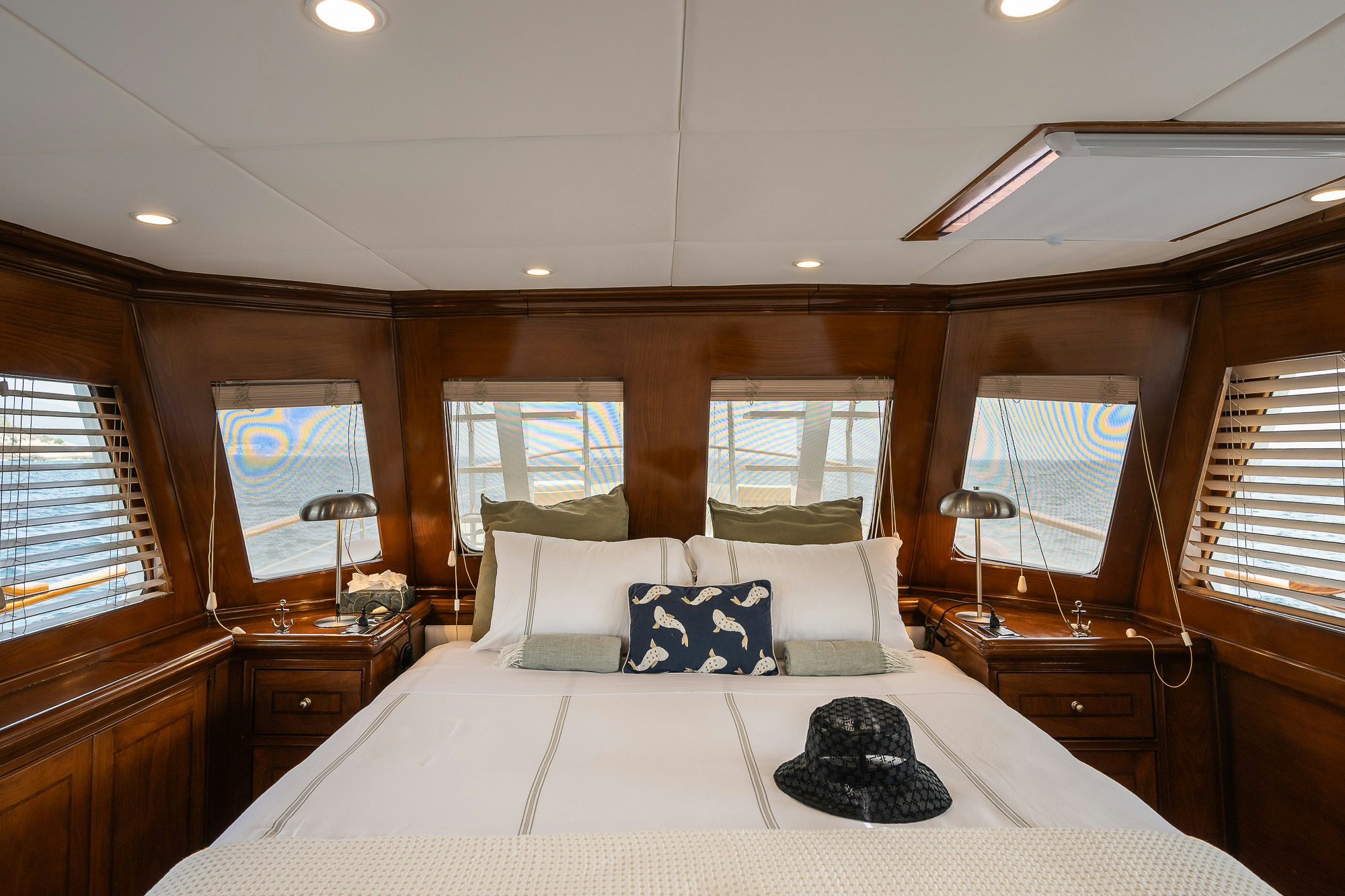 a large bed with a white comforter and pillows in a room with a large window and a aboard BLACK PEPPER Yacht for Sale