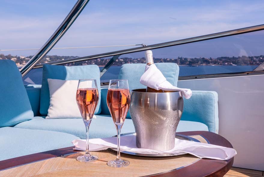 a couple of glasses of wine on a table with a view of the city below aboard CHARADE Yacht for Charter