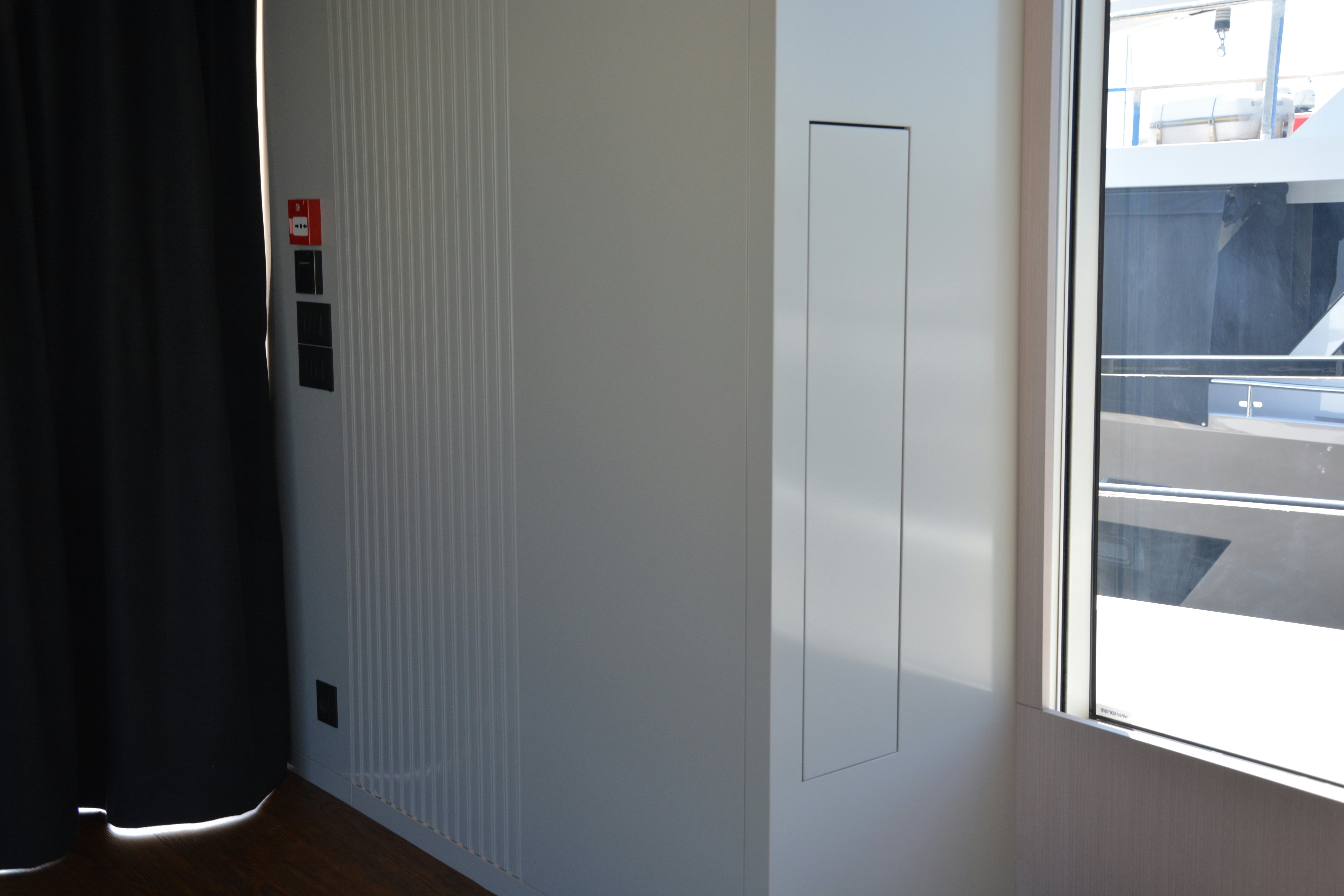 a white door with a red button aboard ZIMA Yacht for Sale