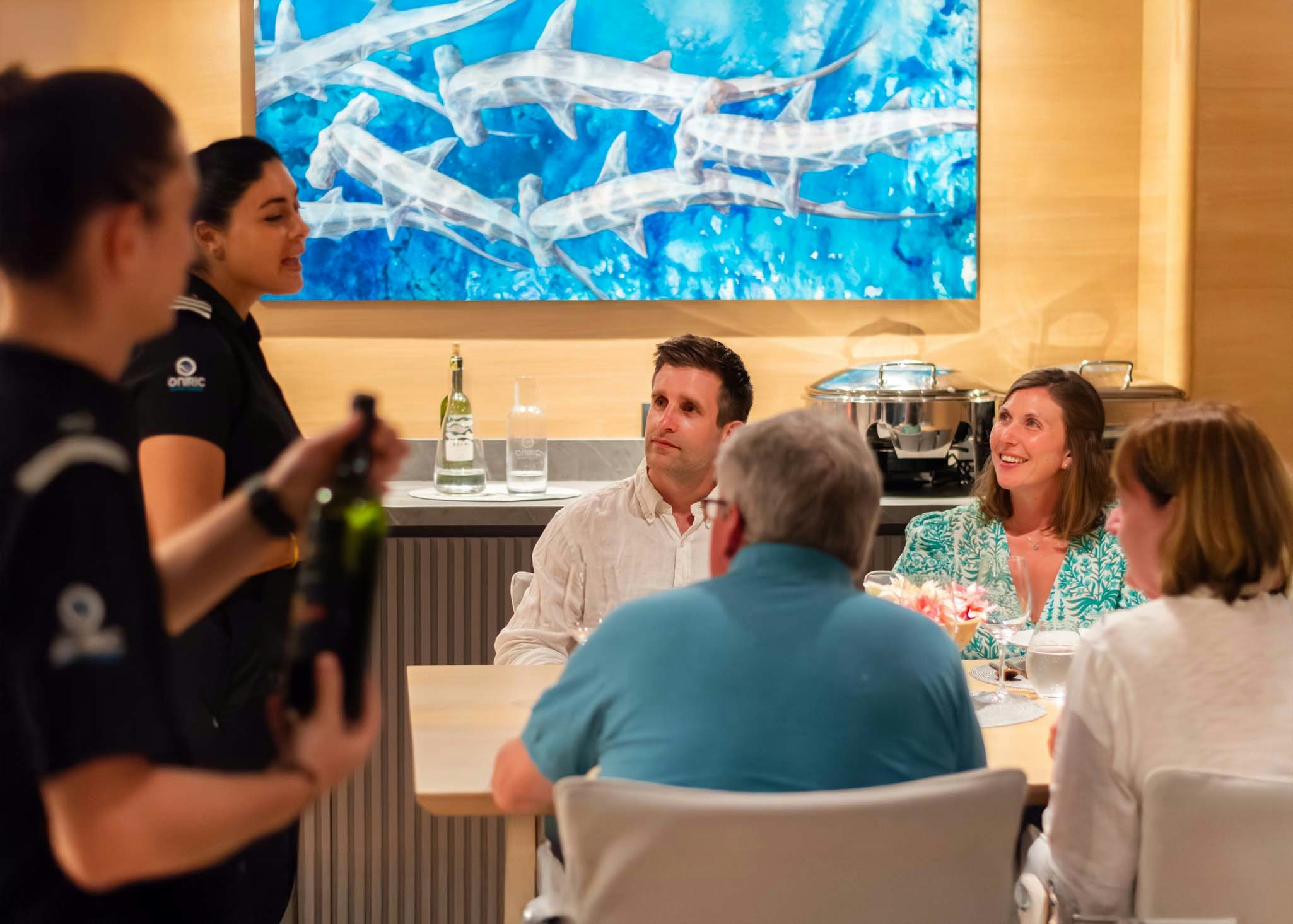 a group of people sitting at a table with a person standing in front of them aboard TRIBUTE - FREDDY'S LEGACY Yacht for Charter