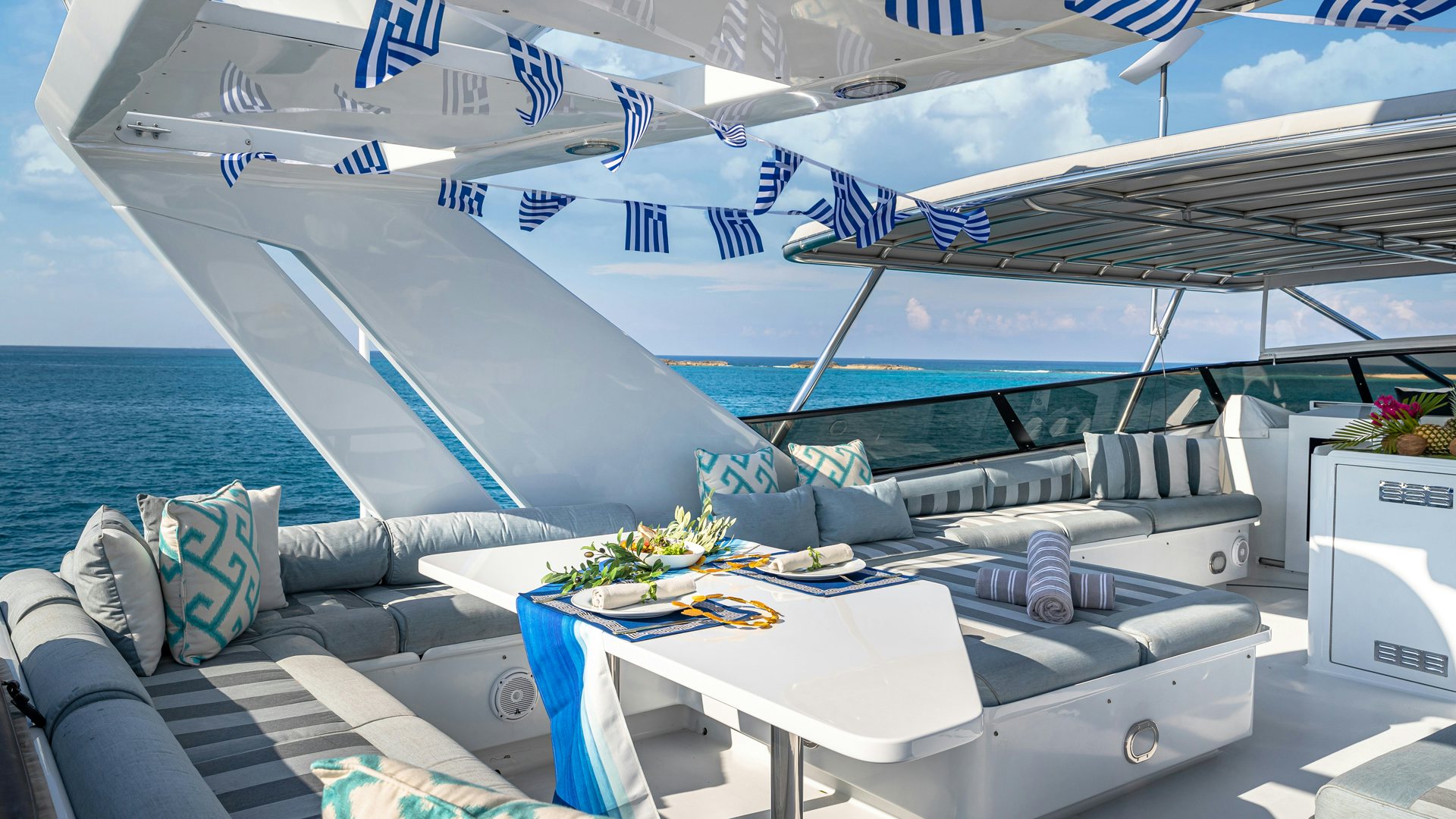 a deck with a large blue and white boat and a table with chairs and a white table with aboard MARGATE Yacht for Sale