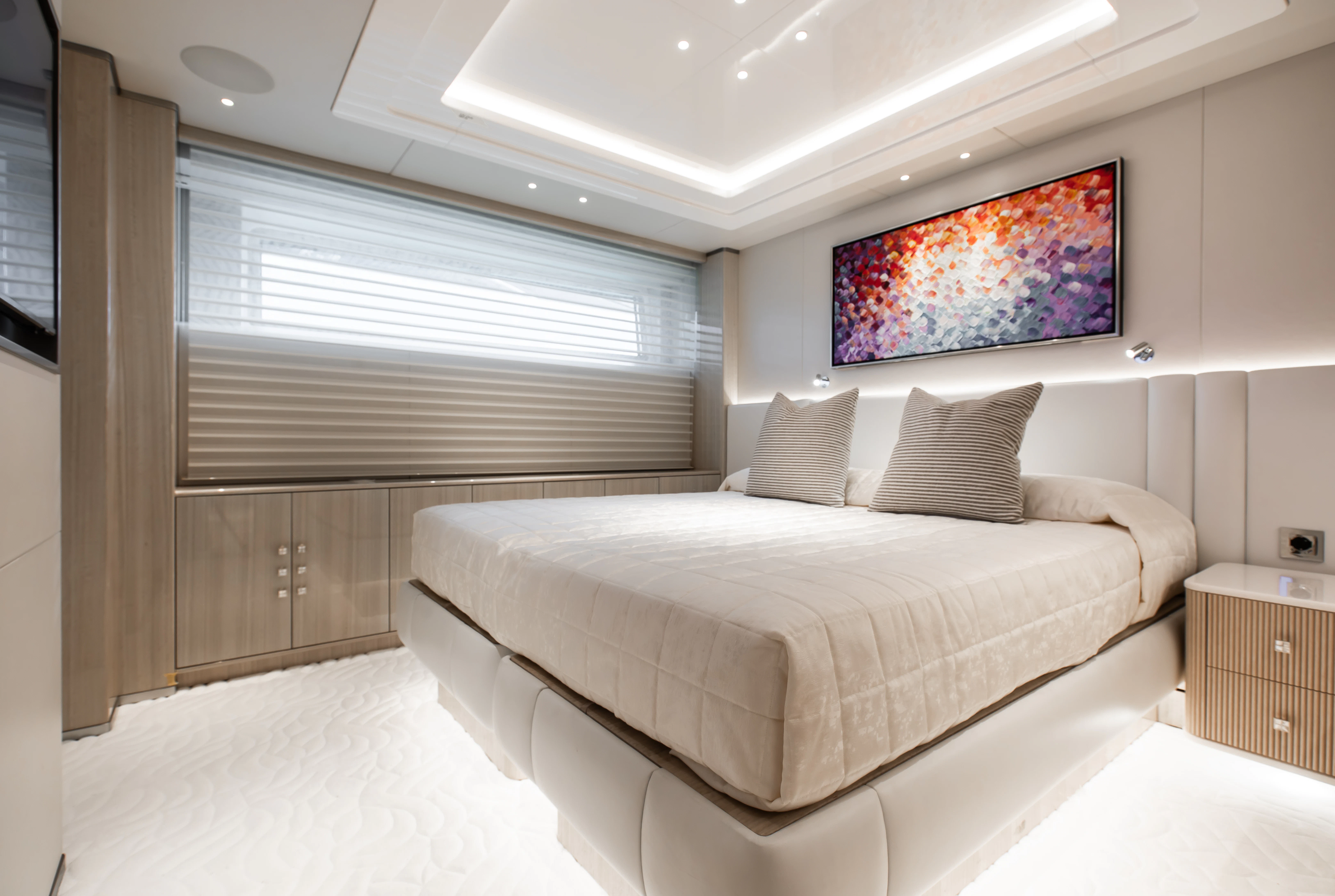 a bedroom with a bed and a painting on the wall aboard PERSEVERANCE Yacht for Charter