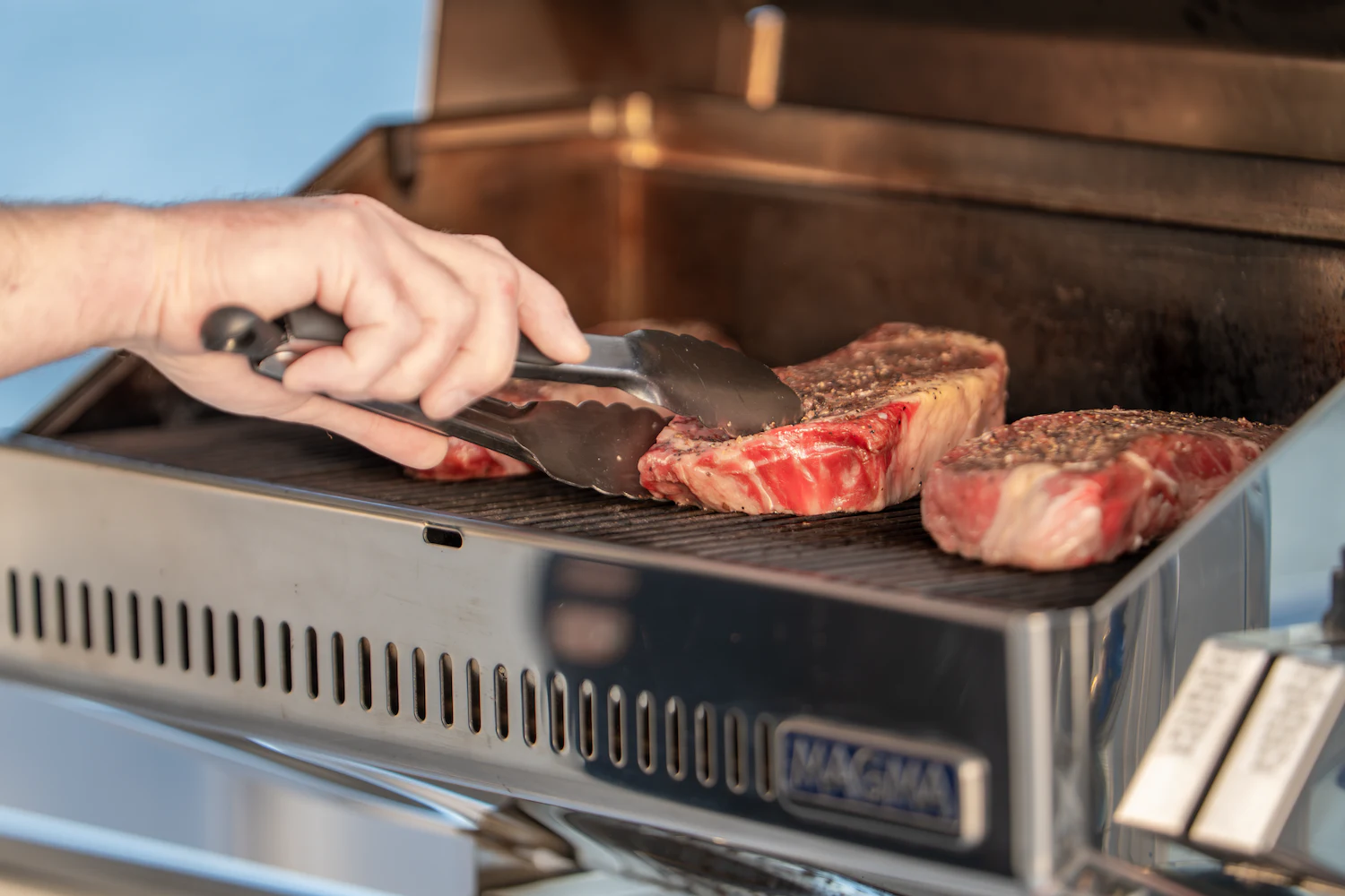 a person cooking meat on a grill aboard SURFBIRD Yacht for Charter