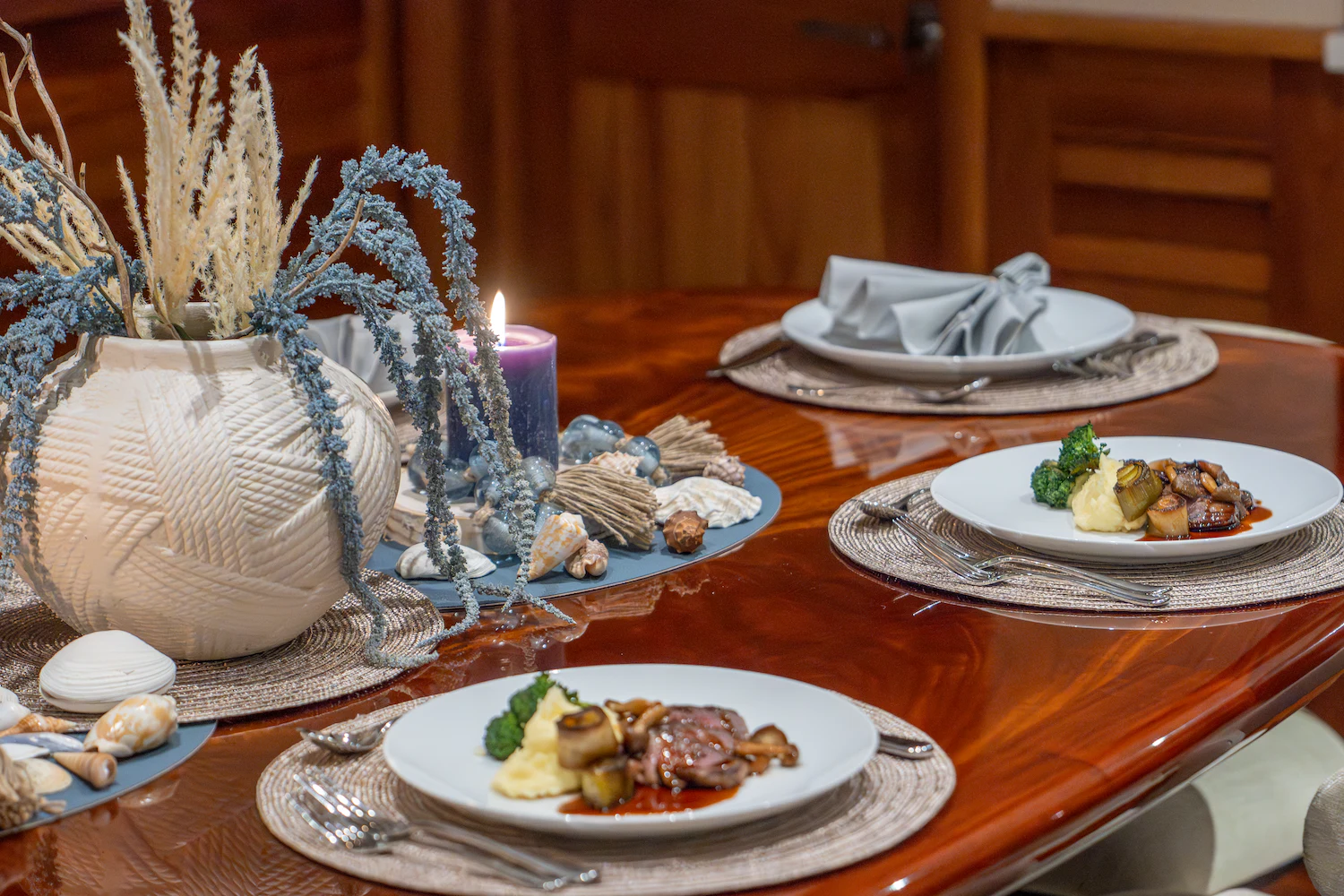 a table with plates of food and a candle aboard SURFBIRD Yacht for Charter