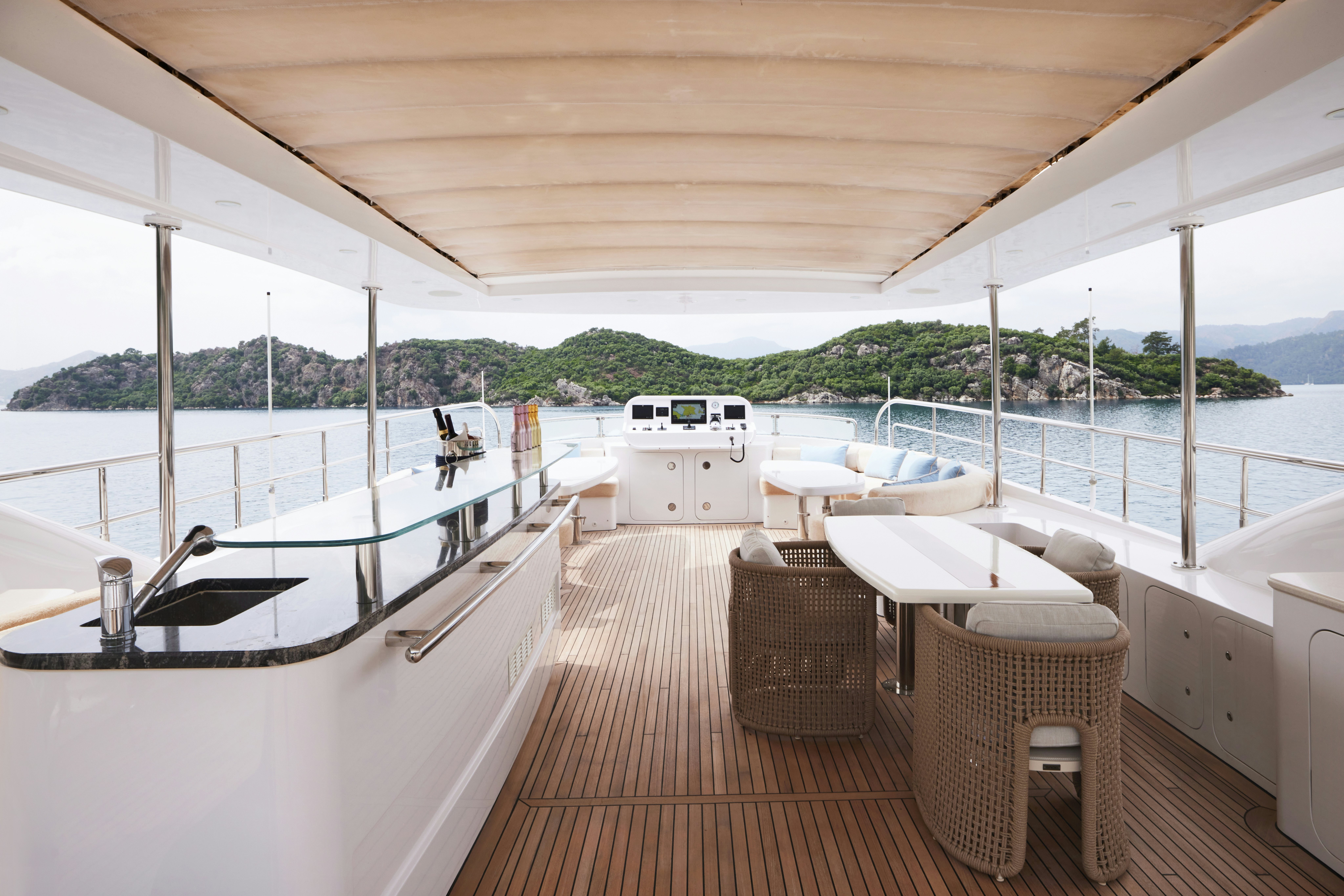 a deck with a table chairs and a view of the water aboard AYSHA Yacht for Sale