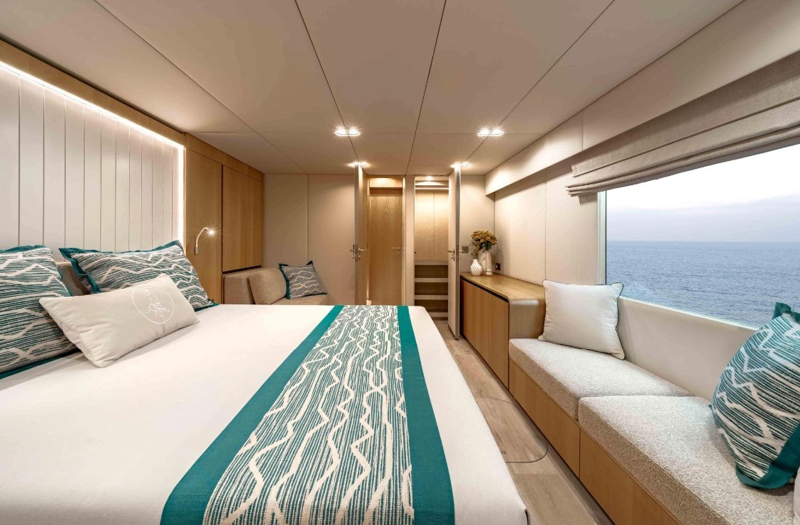 a room with a bed and a large window aboard AMITATU Yacht for Charter