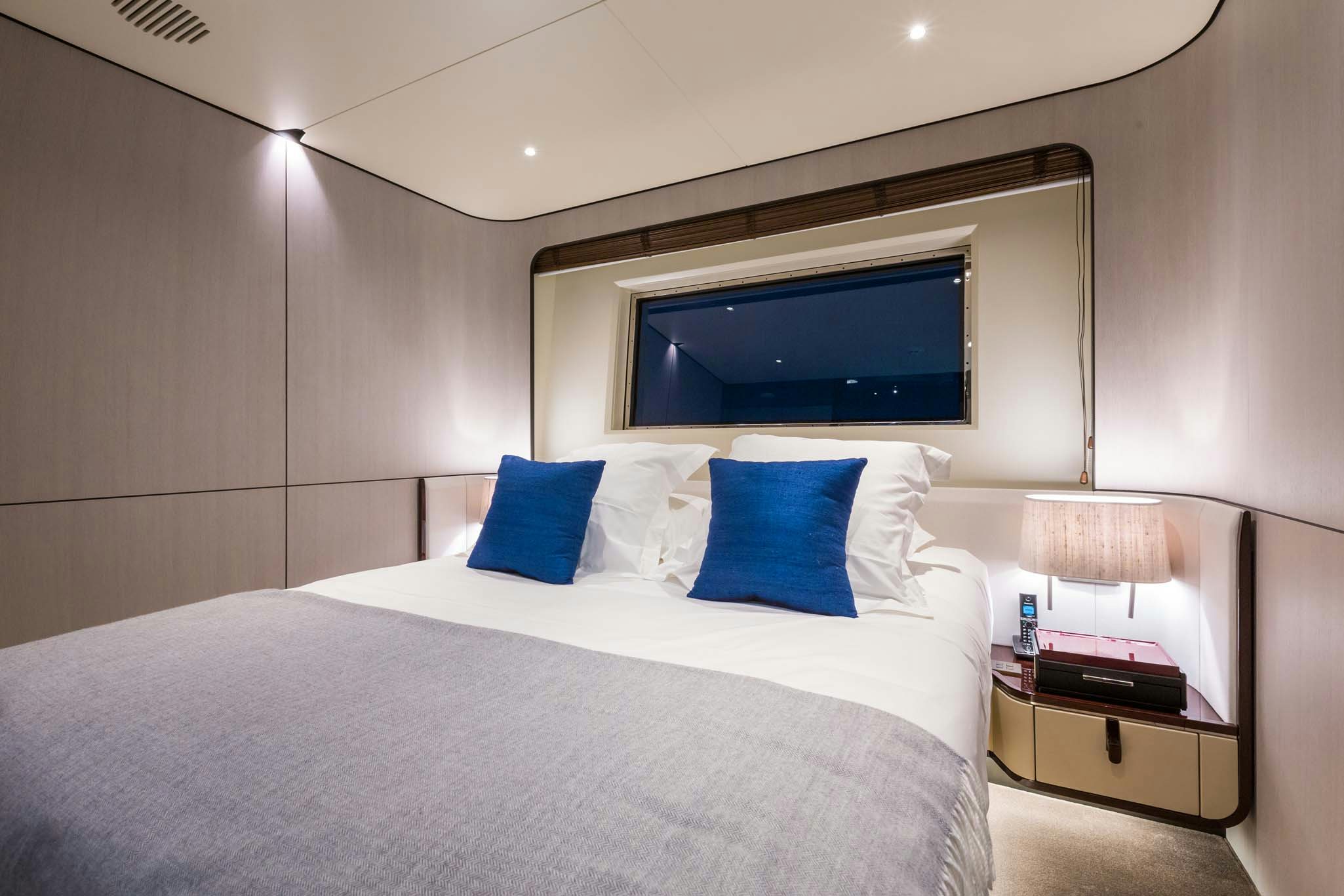 a bed with blue pillows aboard HEED Yacht for Charter