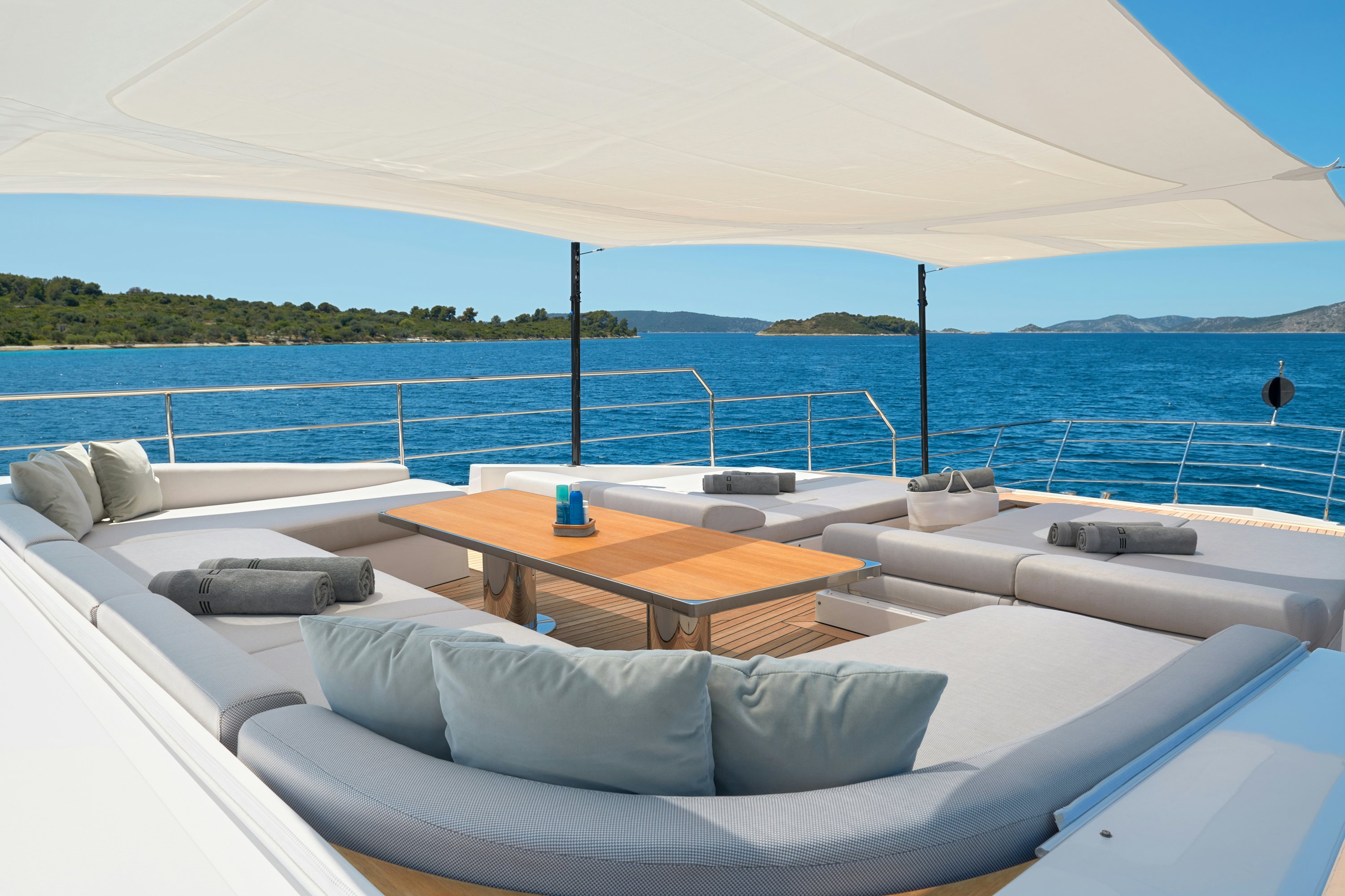 a lounge area with a table and a large body of water in the background aboard HEED Yacht for Sale