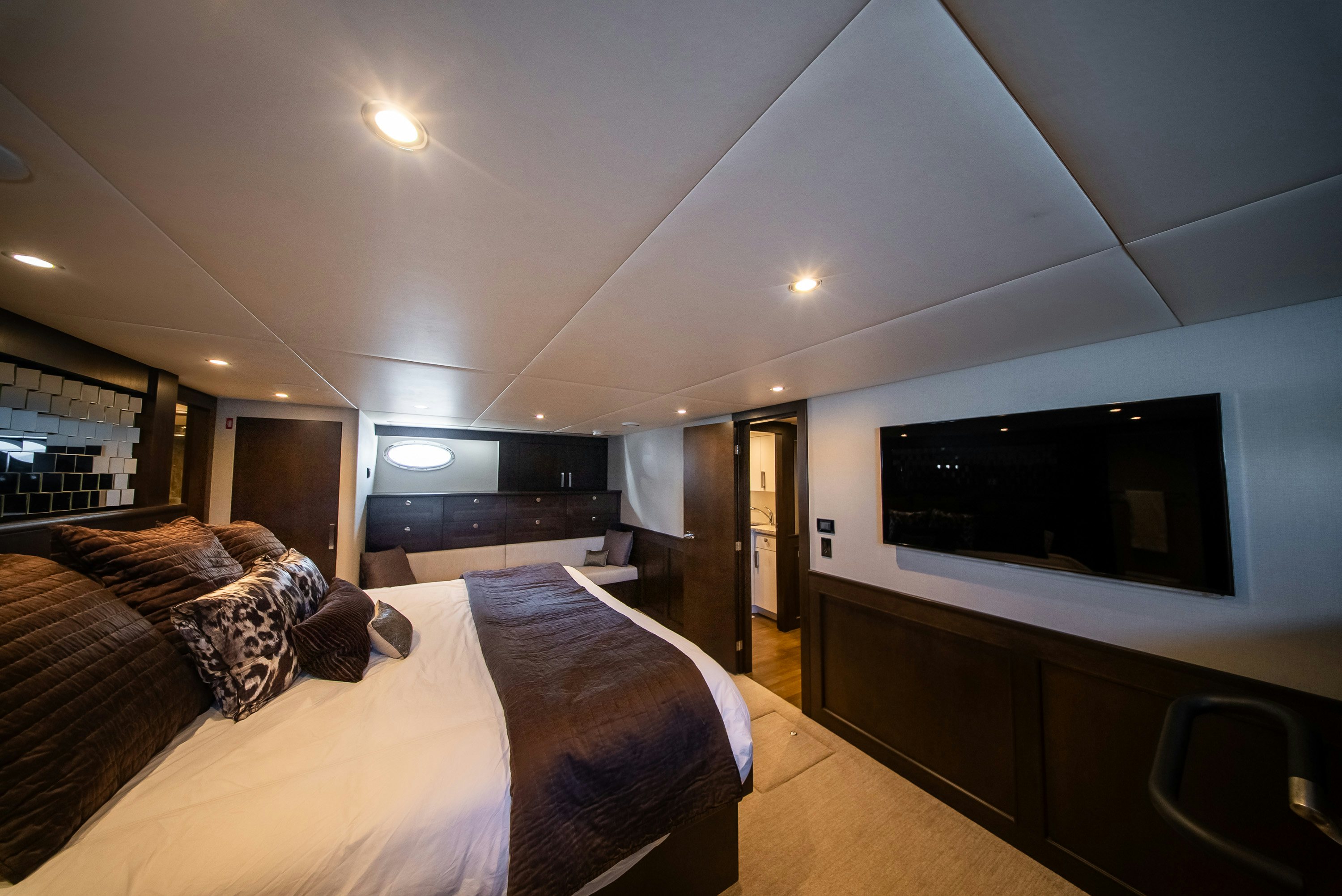 a person lying on a bed in a room with a tv on the wall aboard ENCORE Yacht for Sale