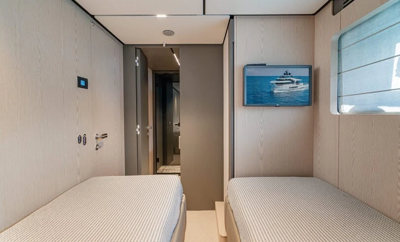 a room with a bed and a television on the wall aboard TRILOGY Yacht for Charter