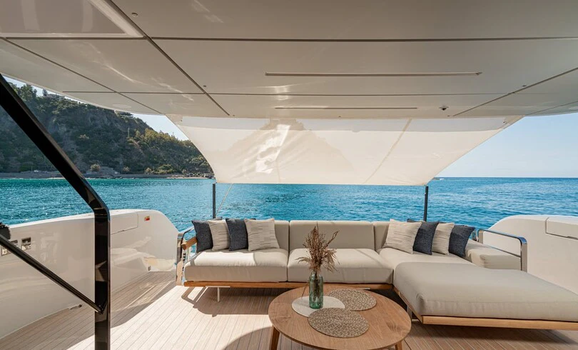 a large white lounge chair on a boat with a large body of water behind it aboard TRILOGY Yacht for Charter