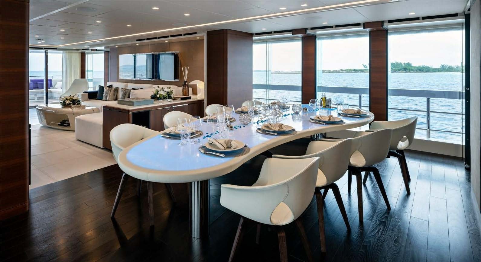 a large dining table with white chairs aboard ELA Yacht for Sale