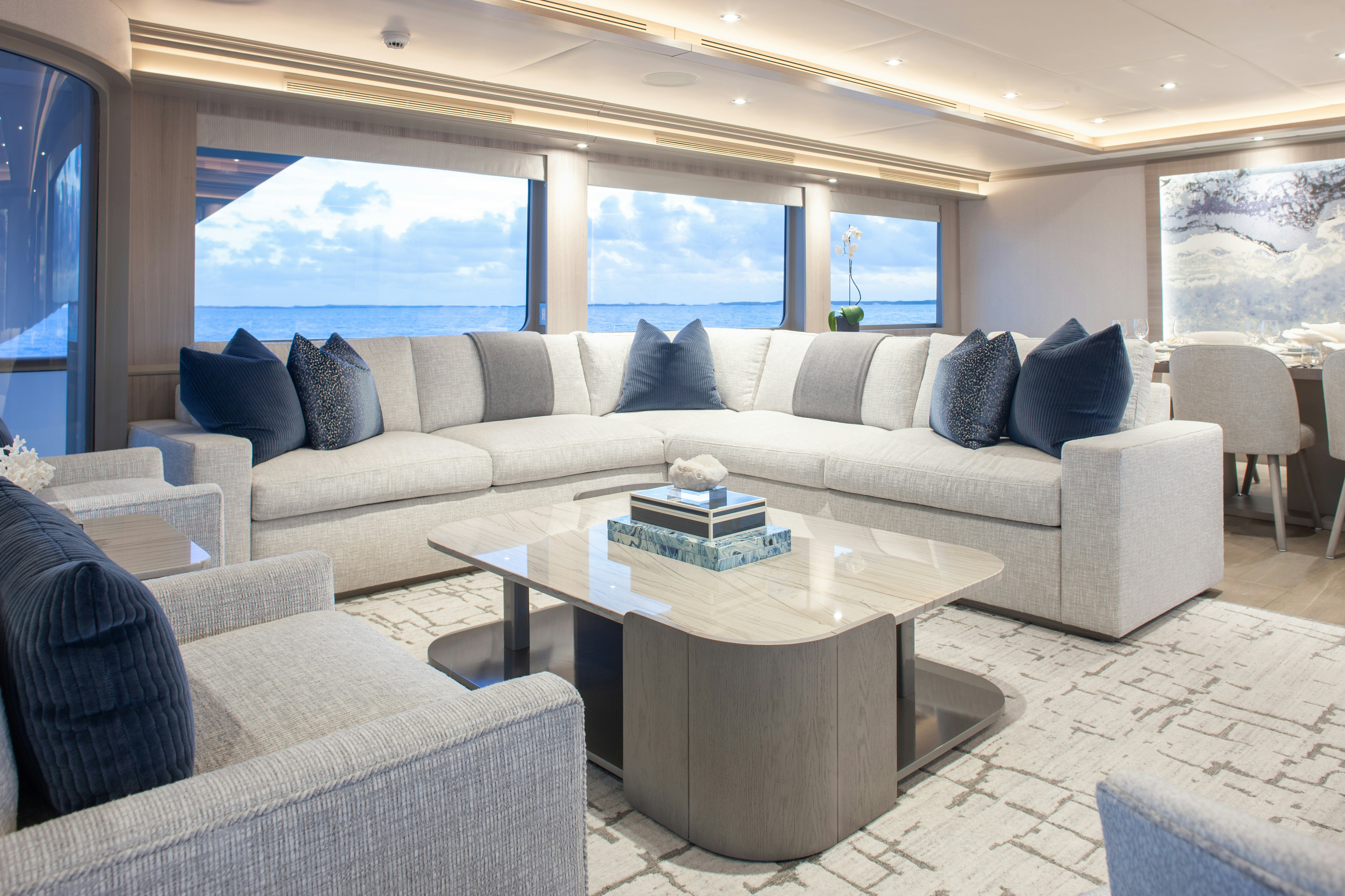 a living room with a large white sofa and a large window aboard NO BAD IDEAS Yacht for Sale